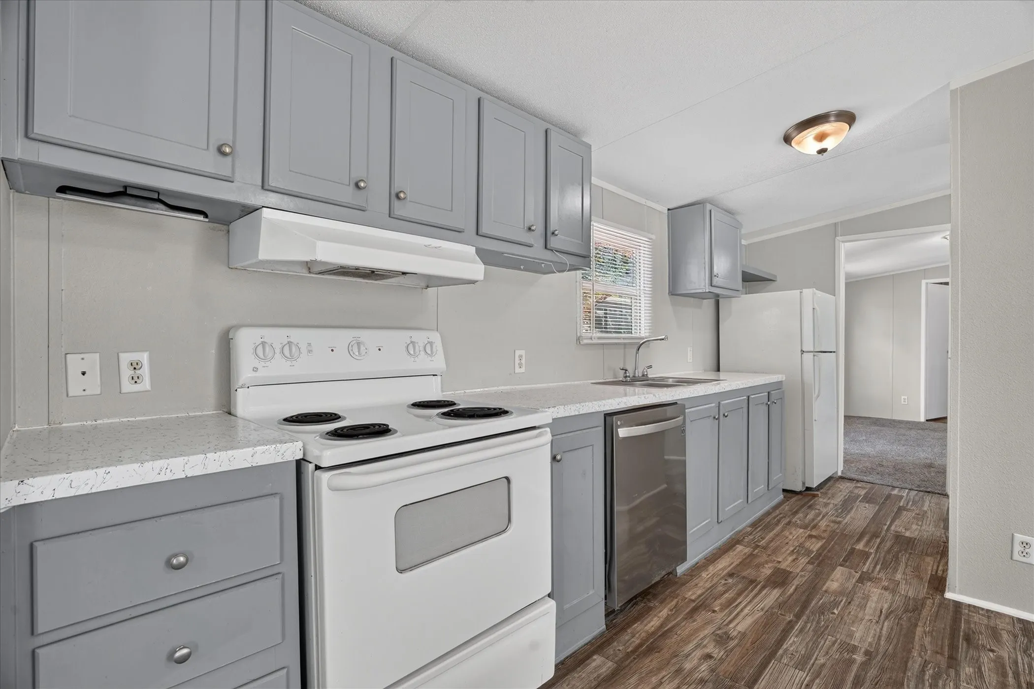 Kitchen featuring wood-finish flooring, gray cabinetry, a white electric range, a stainless steel dishwasher, and a double-basin sink