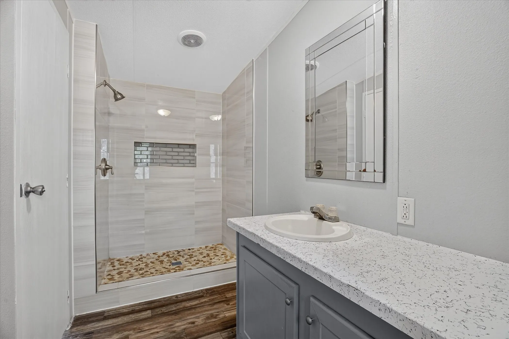 Walk-in shower with tile surround and pebble-finish flooring