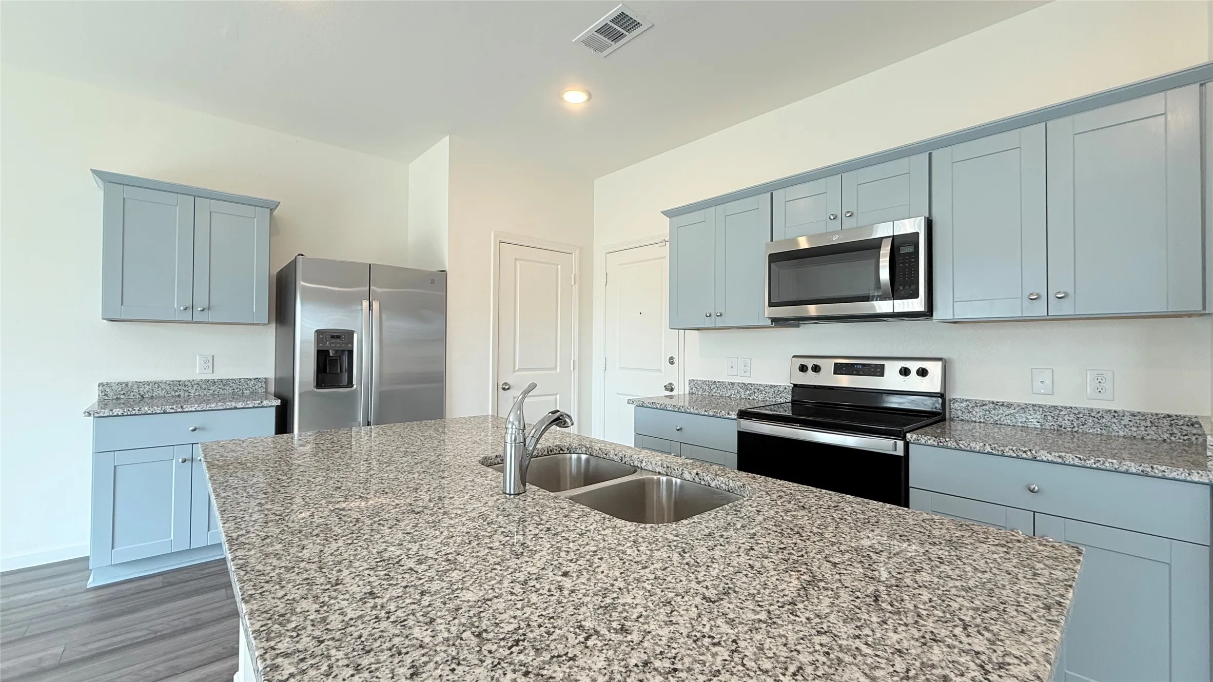 Kitchen featuring a double basin sink, light-toned cabinetry, stainless steel appliances, and speckled countertops