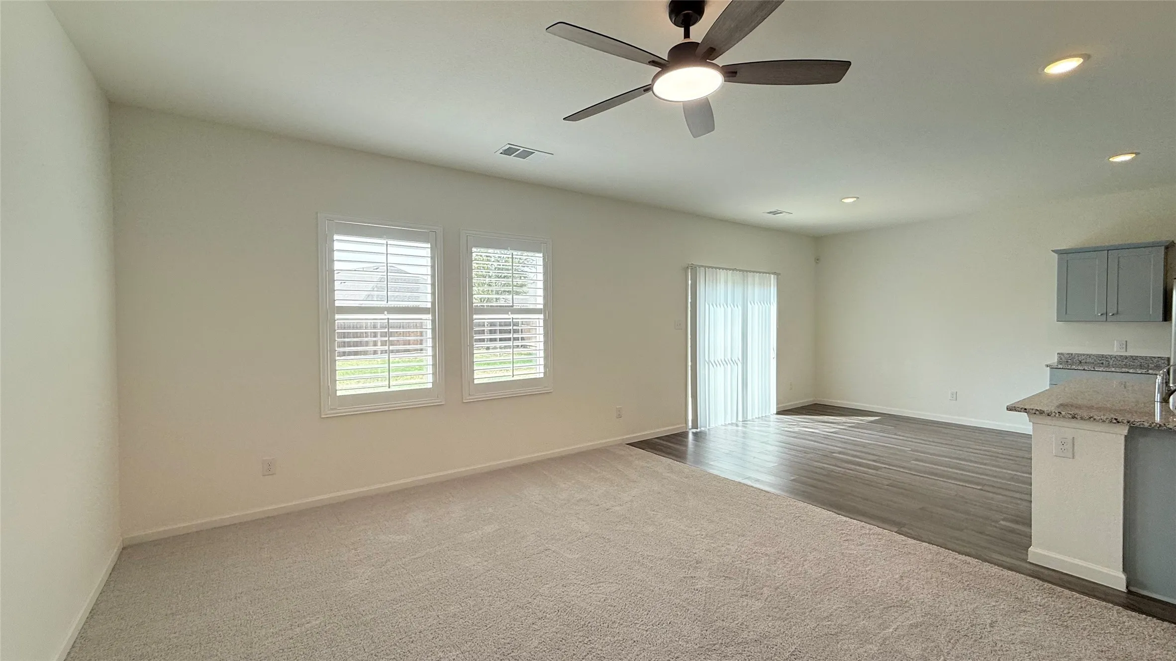 Vaulted ceilings, a ceiling fan with integrated lighting, recessed lighting, and wood-finish flooring
