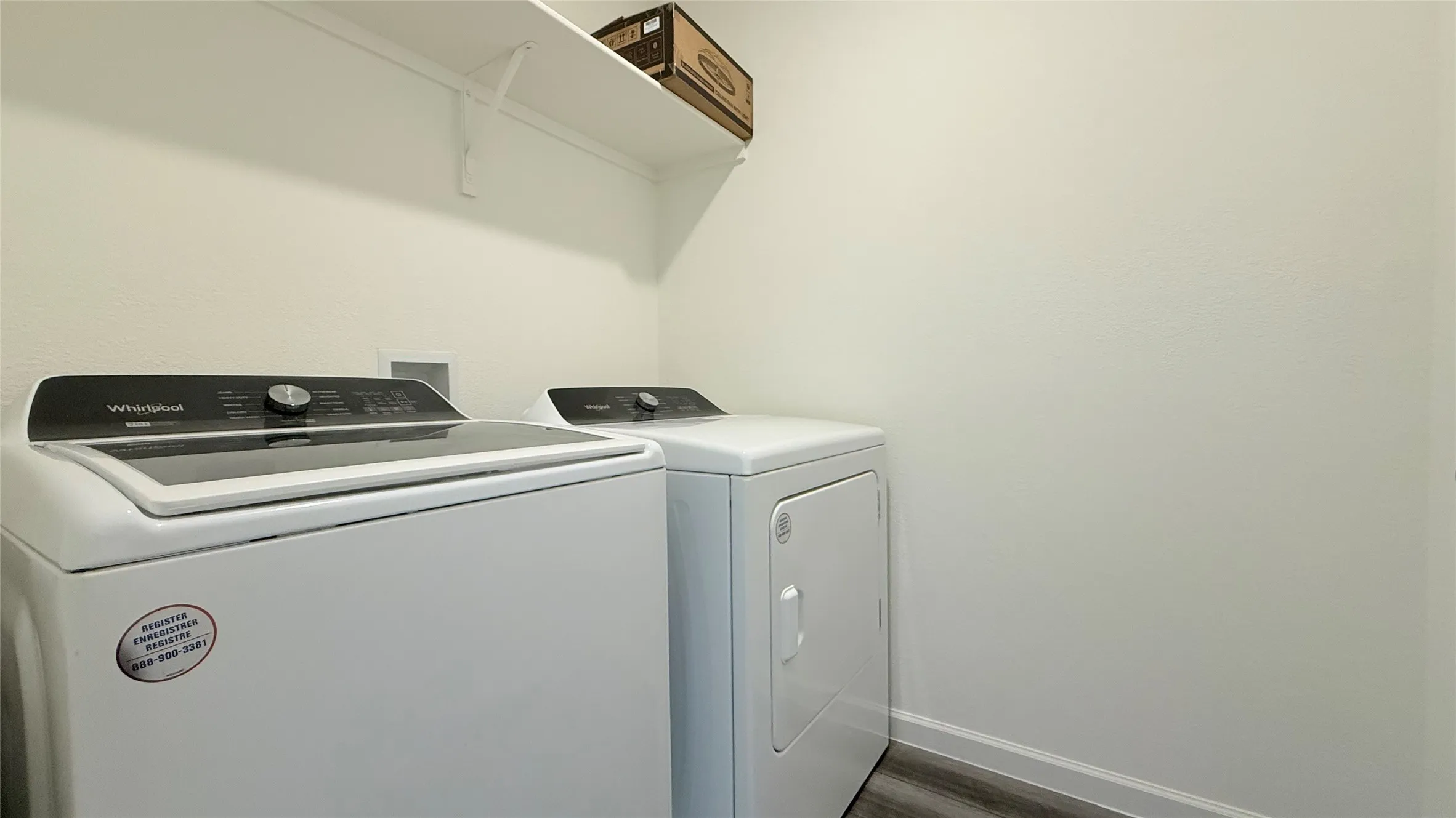 Dedicated laundry area featuring a washer, dryer, wall-mounted shelving, and wood-finish flooring