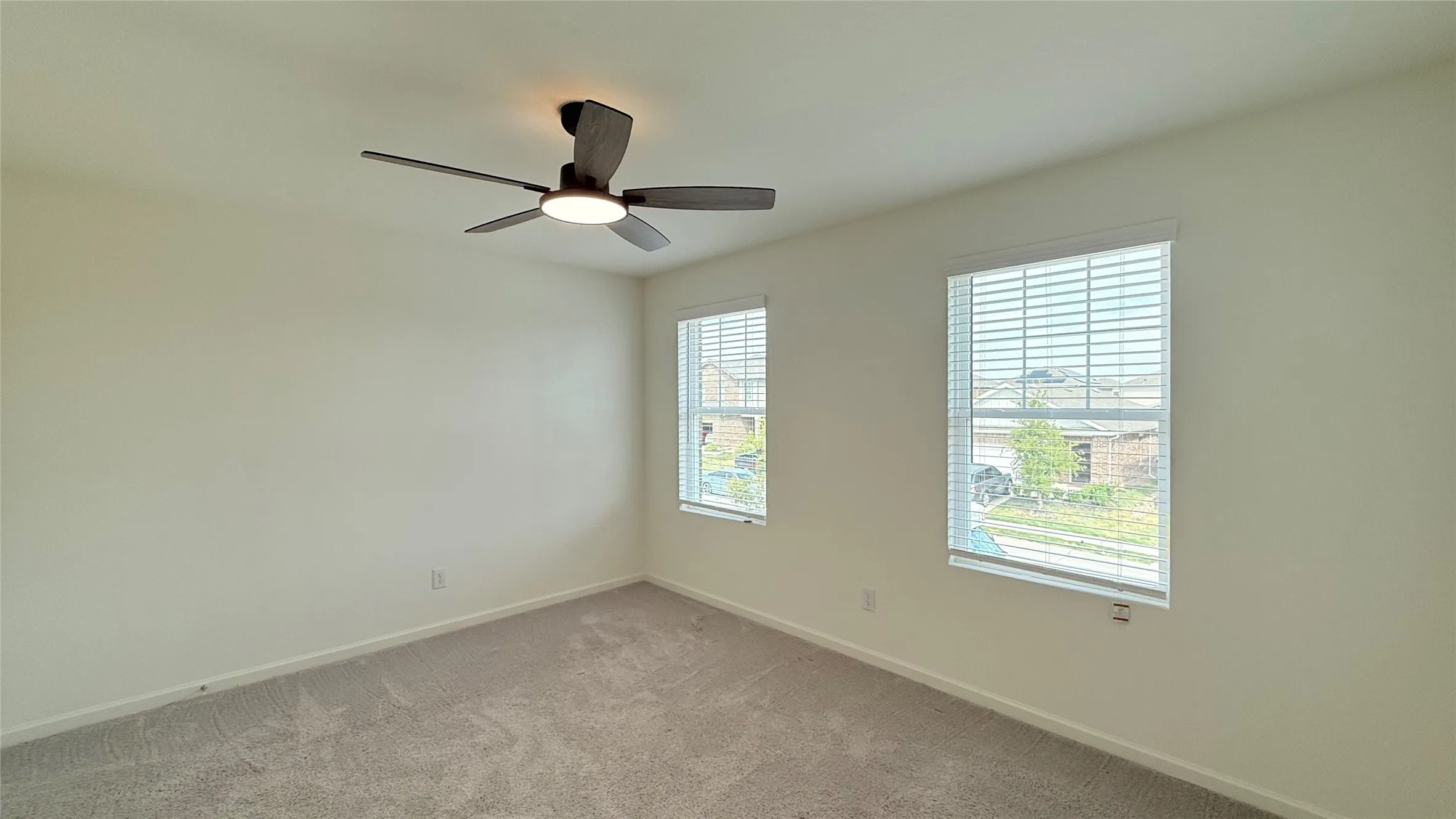Neutral wall paint, ceiling fan with integrated lighting, two windows with blinds, and carpeting