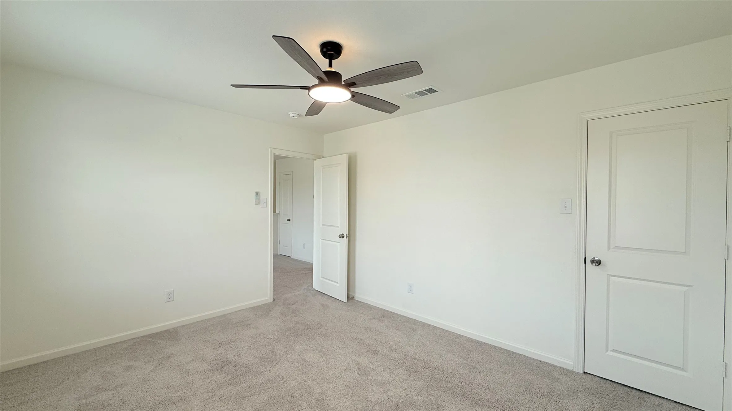Recessed ceiling fan with integrated lighting, soft grey carpeting, and white paneled doors