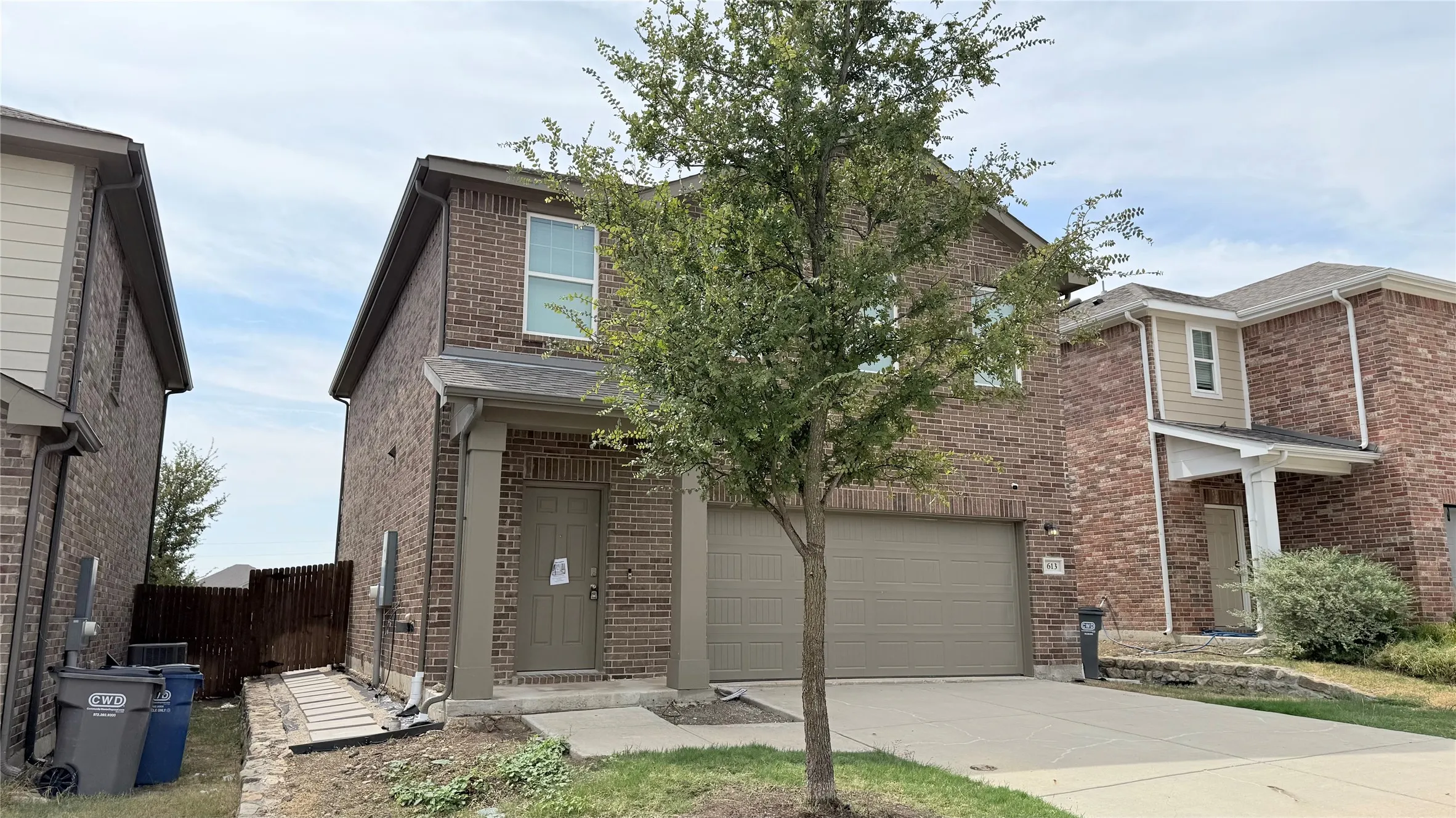 Brick exterior with an attached garage, covered entry, and a well-maintained tree