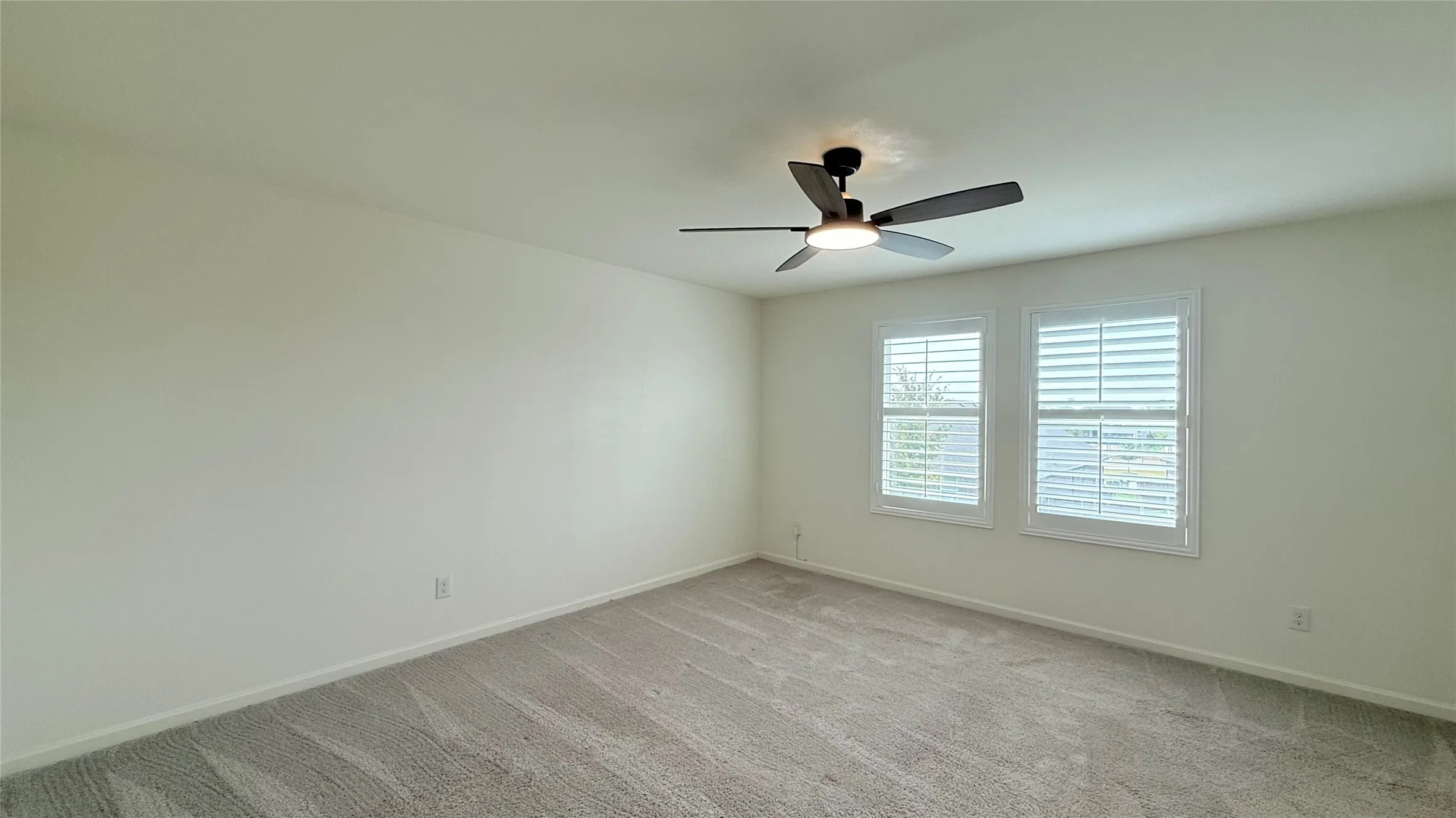 Recessed lighting, ceiling fan, two windows with plantation shutters, and neutral carpeting