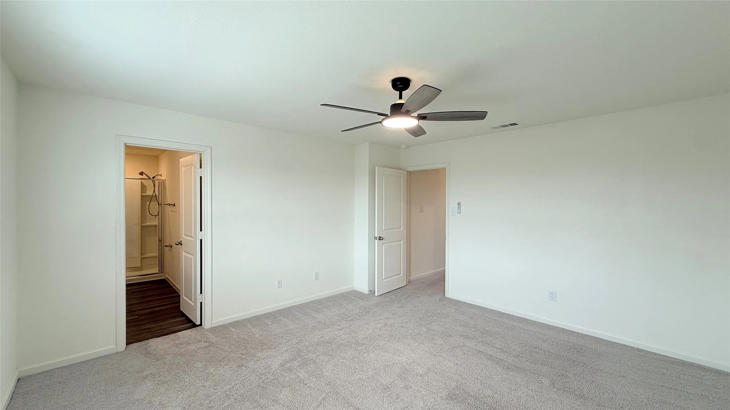 Spacious room featuring light-toned carpet, a contemporary ceiling fan with integrated lighting, and white walls