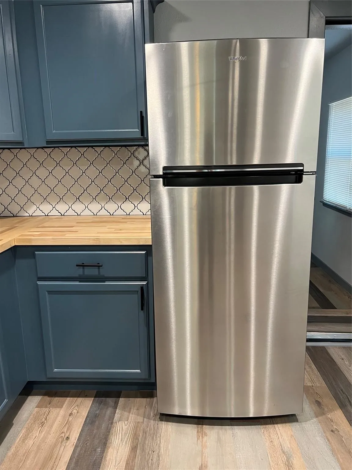 Stainless steel refrigerator and custom cabinetry with matte hardware