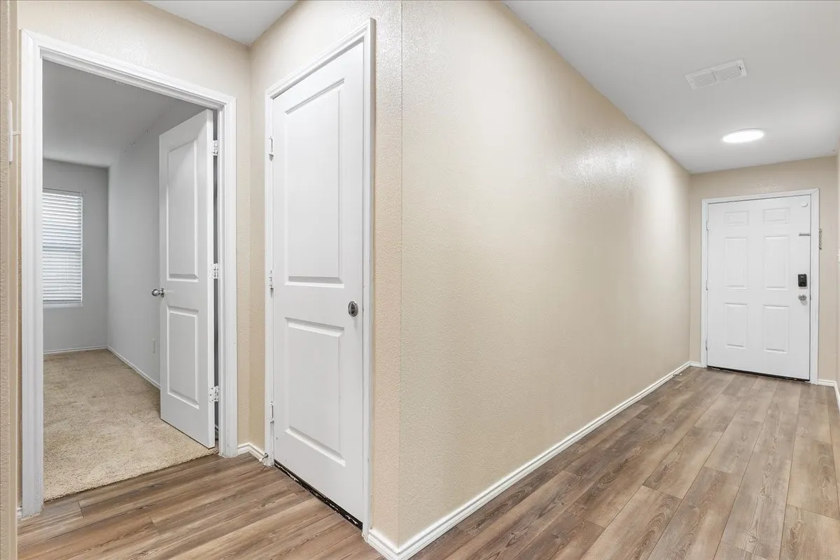 Wood-finish flooring, white paneled doors, ceiling-mounted lighting, and neutral wall tones