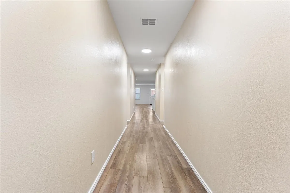 Hallway featuring wood-finish flooring, recessed lighting, and neutral-toned textured walls