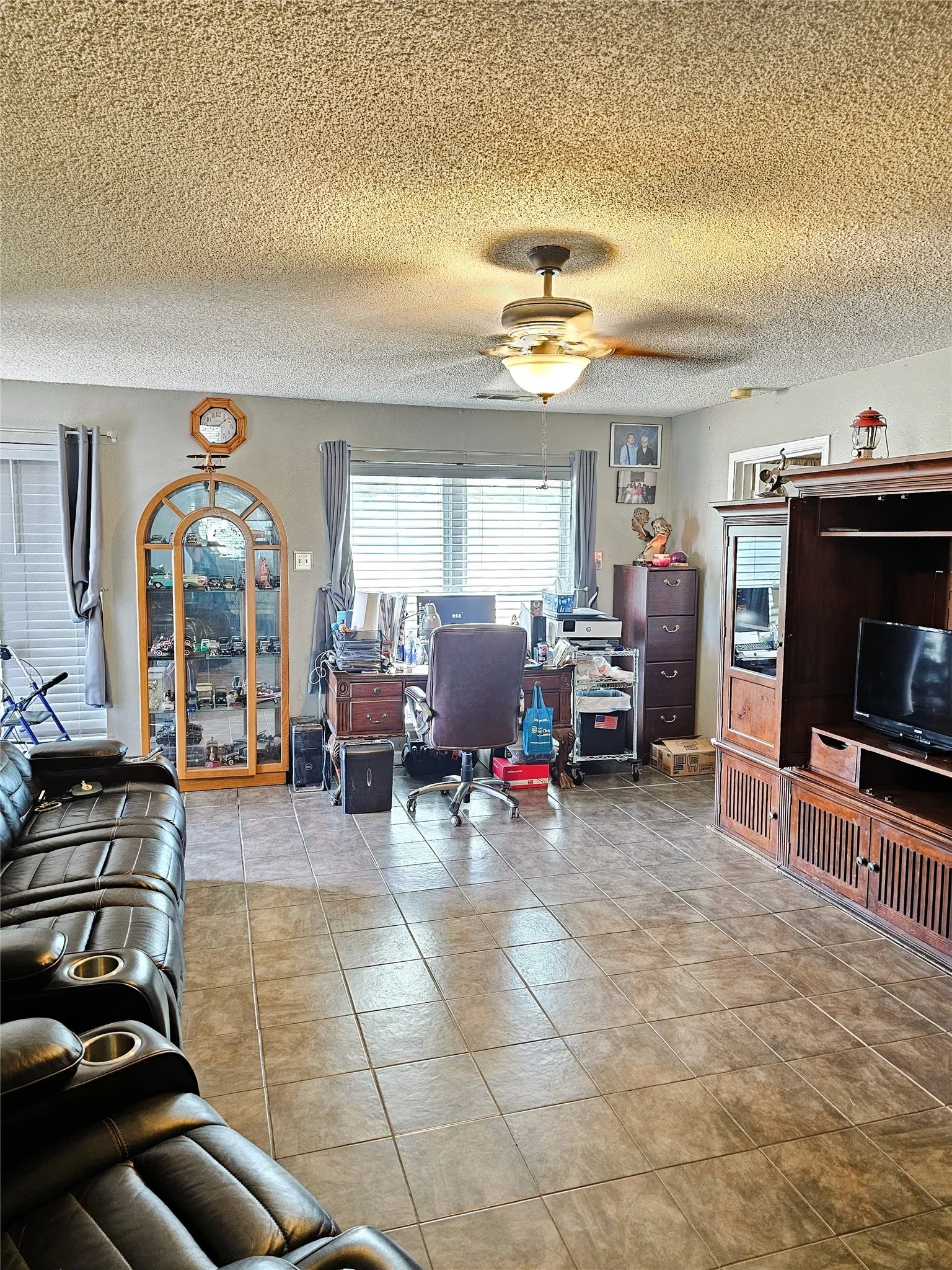 Tile flooring, ceiling fan with integrated lighting, window with horizontal blinds, architectural wall niche, wood-finish built-in cabinetry