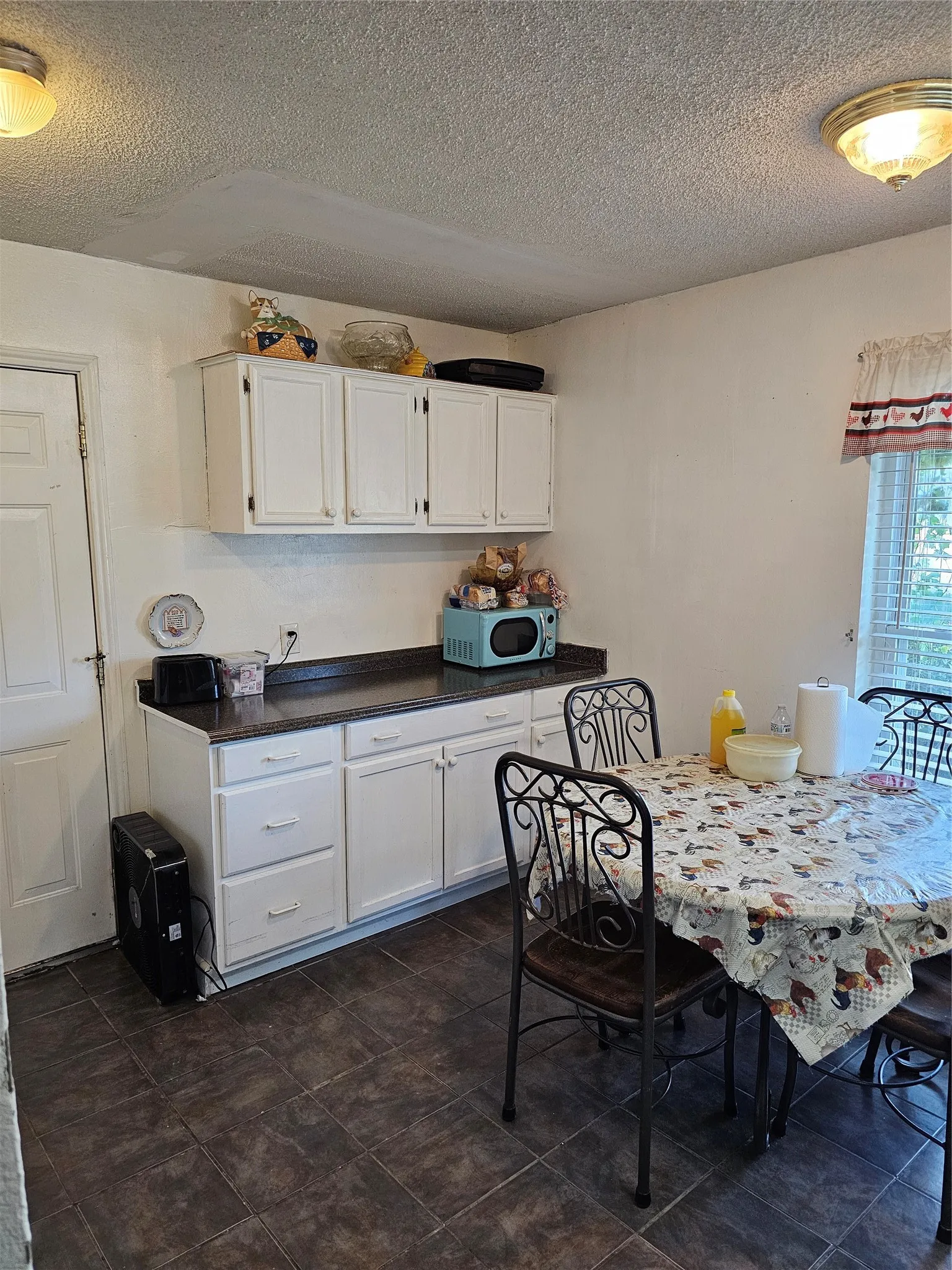 White cabinetry with dark countertops, tile flooring, and a flush mount ceiling light fixture