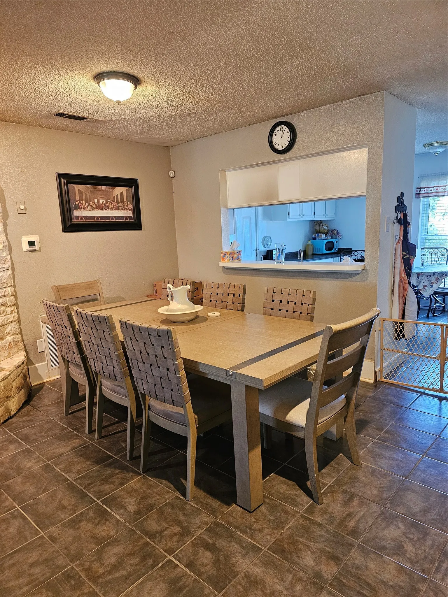 Dining area featuring tile flooring, a pass-through window, and a built-in wall niche