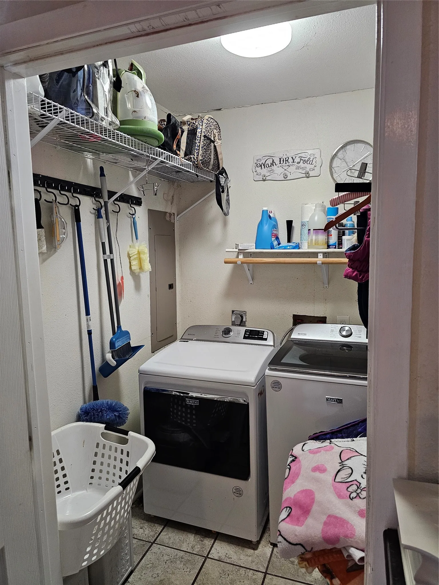 Laundry area featuring tile flooring, a built-in wall shelf, and overhead lighting