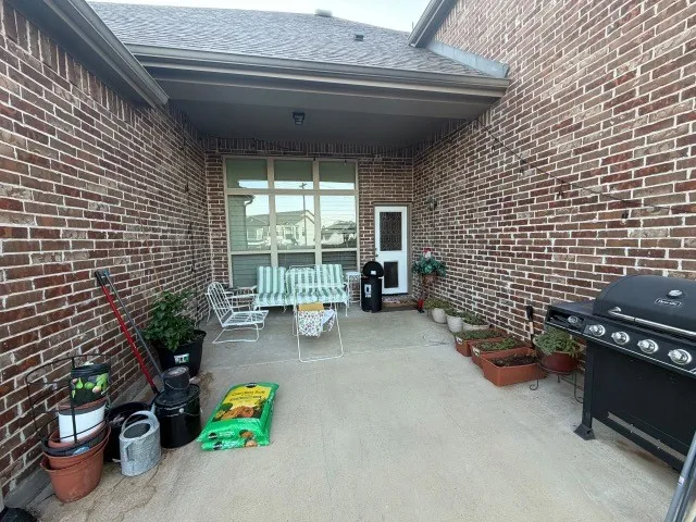 Brick exterior featuring a covered patio with a concrete surface and a full-light panel door