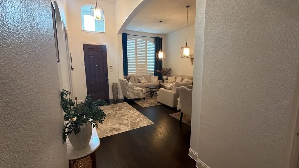 Arched entryway with a dark wood-finish door, high ceilings, dark wood-finish flooring, and pendant lighting fixtures