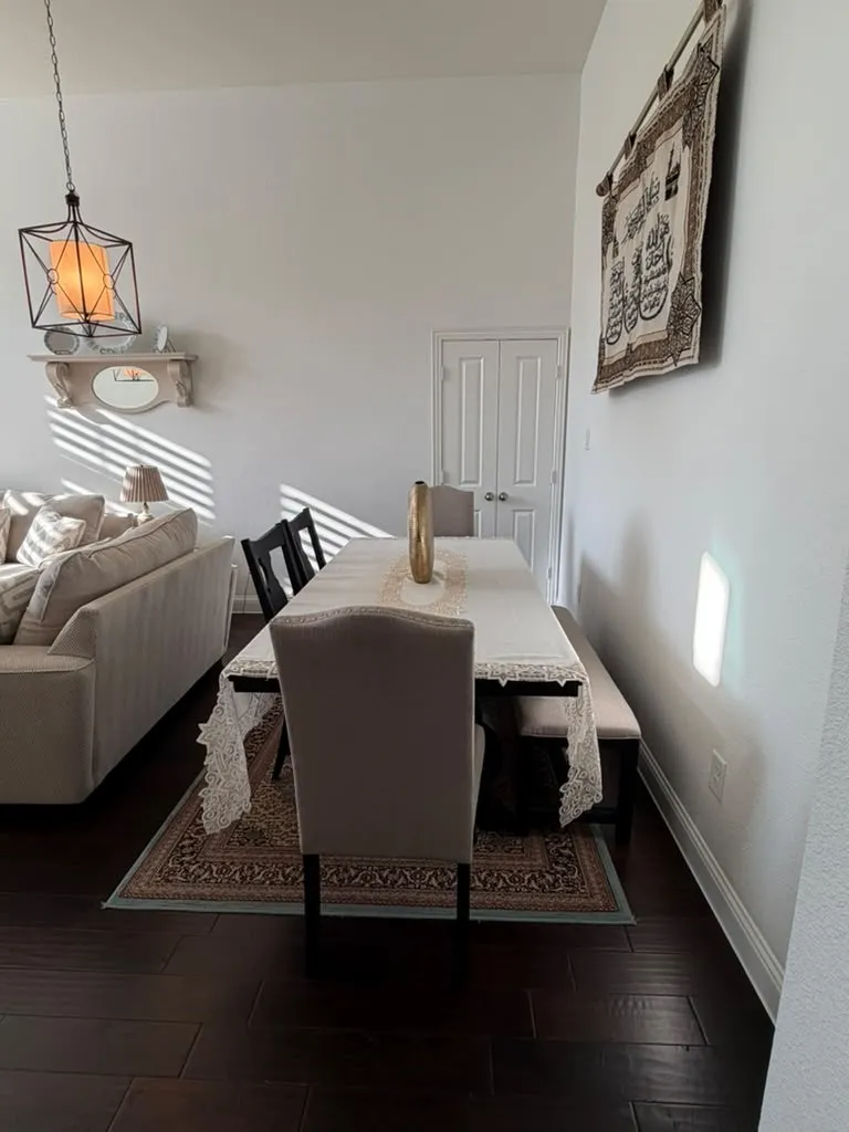 Dark wood-finish flooring with crisp white baseboards, a pendant light fixture, and a built-in wall shelf