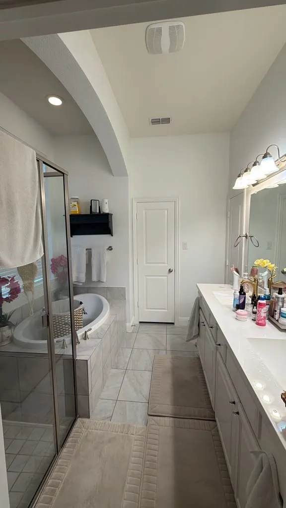 Dual vanity with undermount sinks, a built-in soaking tub, and a separate glass-enclosed shower
