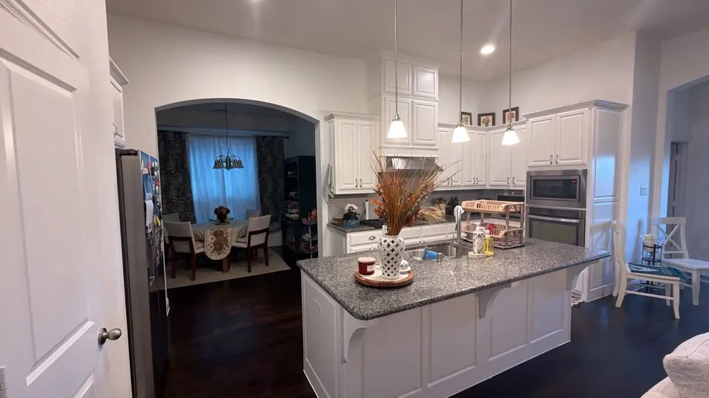 Kitchen featuring white cabinetry, a large kitchen island with a dark countertop, stainless steel appliances, and pendant lighting