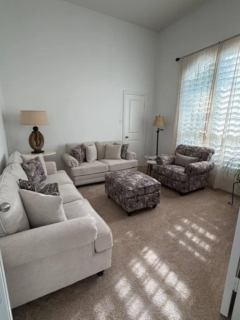 Vaulted ceiling, neutral wall paint, carpeted flooring, and a window with natural light