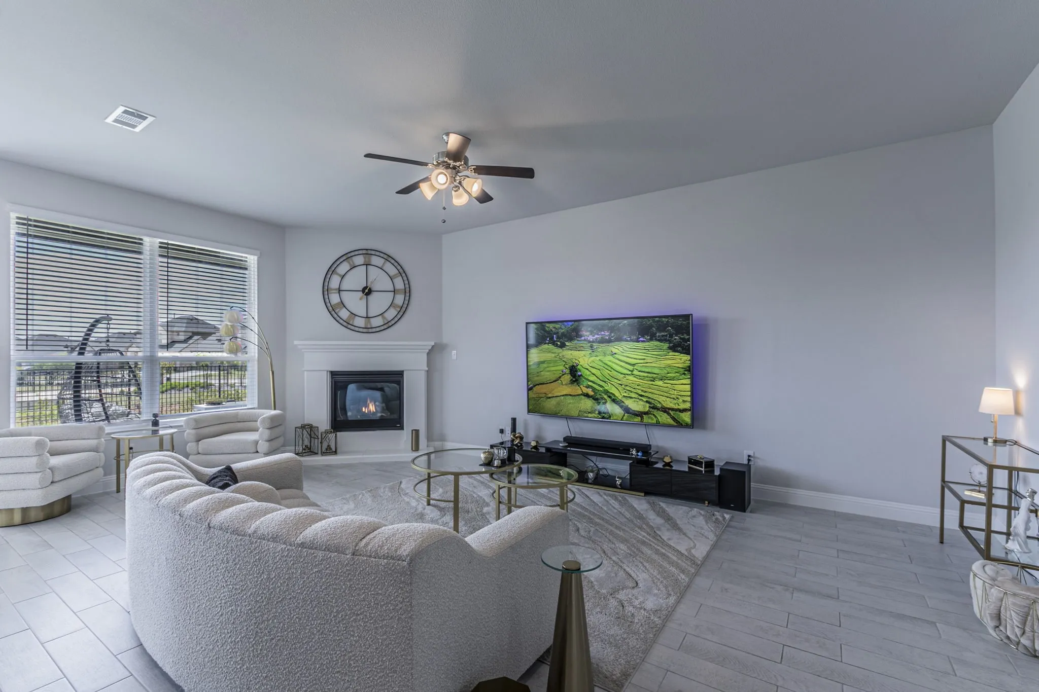 Living area with a ceiling fan, a glass covered fireplace, and light wood-style floors