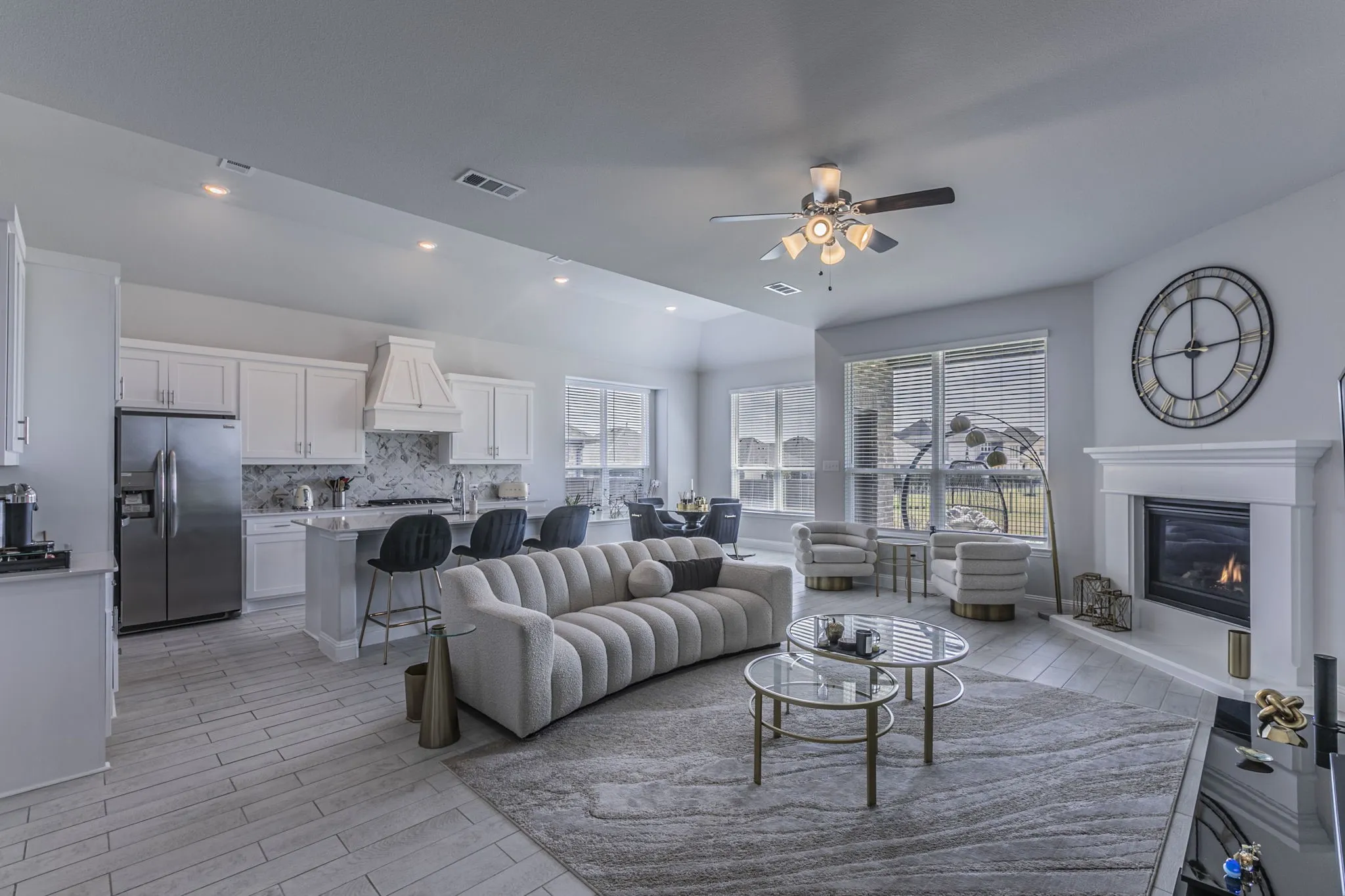Living room featuring ceiling fan, wood tiled floors, a glass covered fireplace, recessed lighting, and lofted ceiling