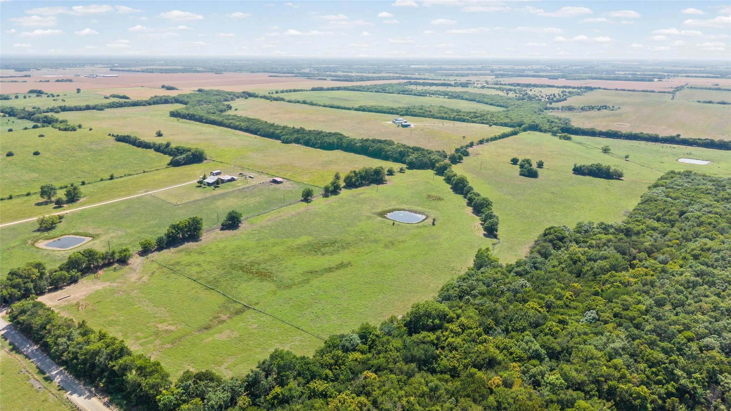 Expansive acreage featuring cultivated fields, wooded areas, and multiple ponds