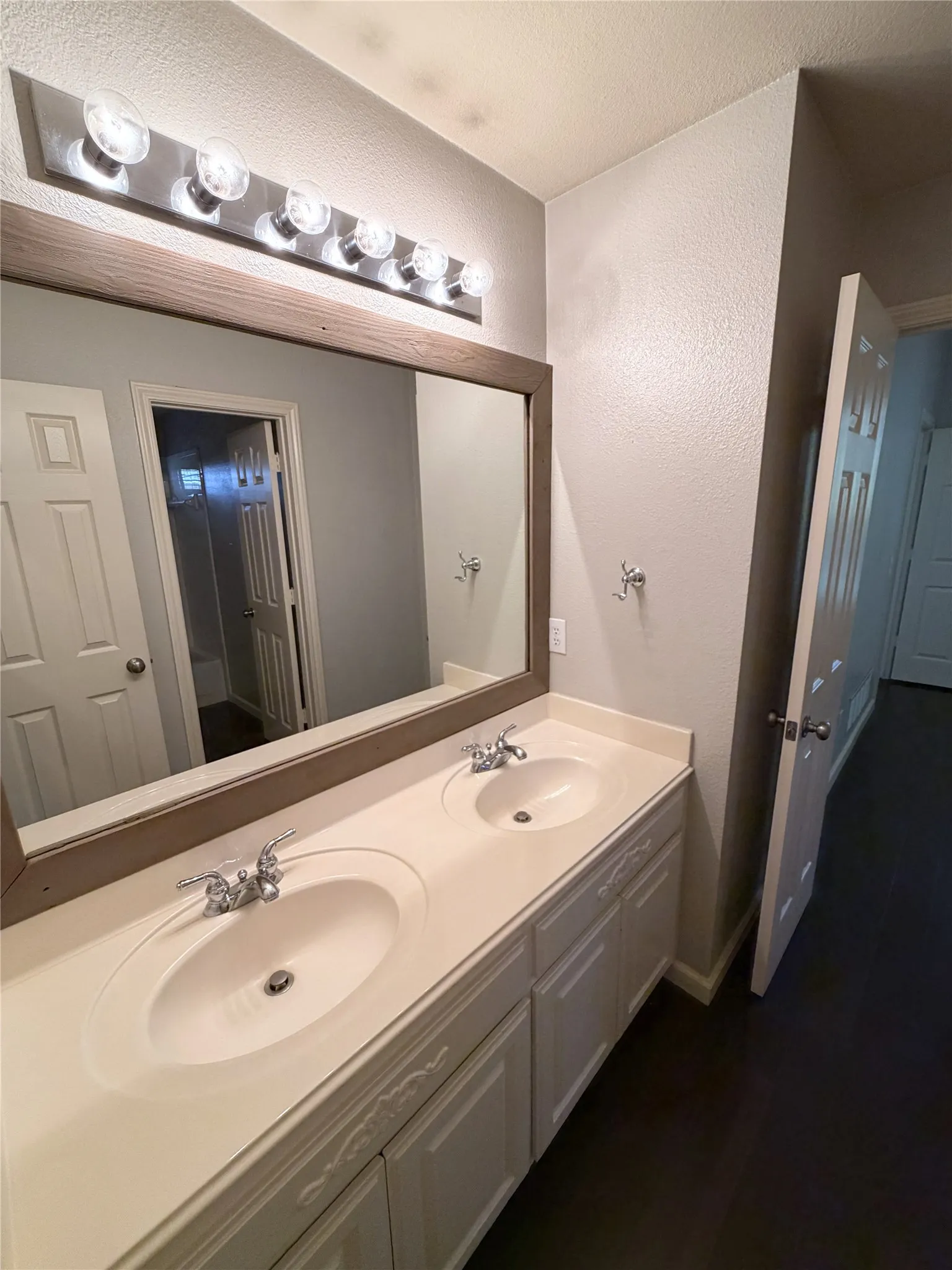 Double vanity with integrated sinks, framed mirror, and overhead strip lighting