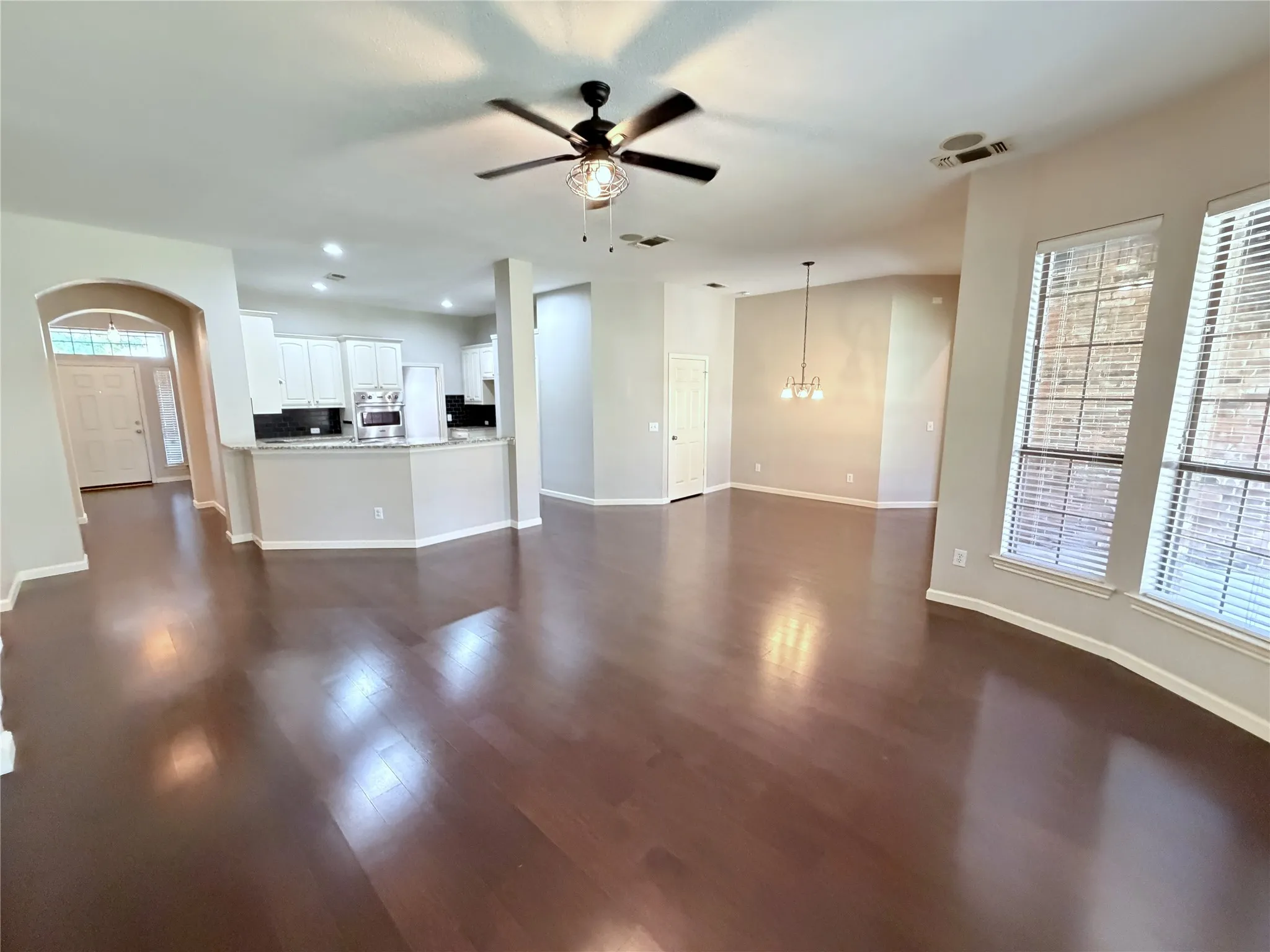 Wood-finish flooring throughout, white cabinetry, integrated microwave, pendant lighting, and multiple windows
