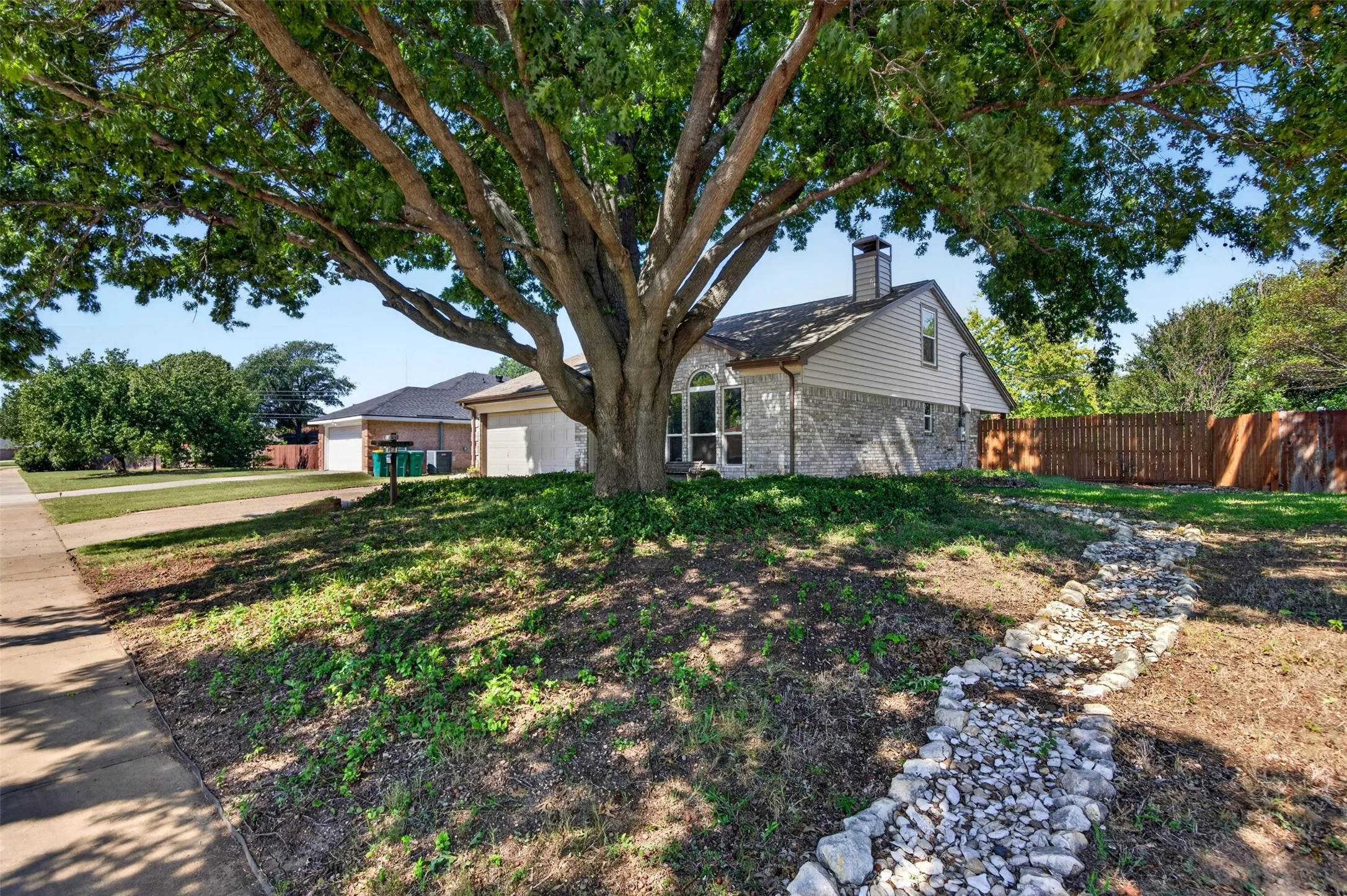 Stone and siding exterior with an arched window, a prominent chimney, and a fenced perimeter