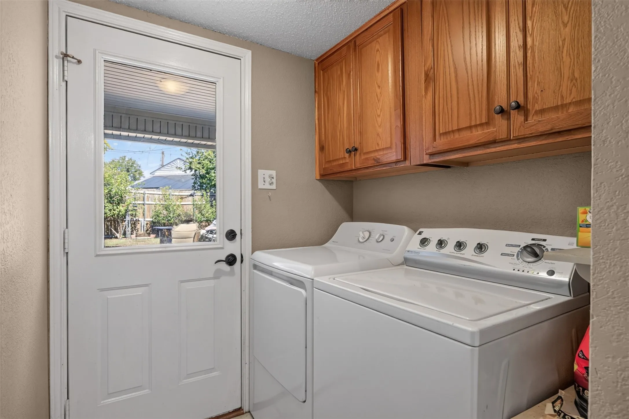 Laundry area featuring wood cabinetry, white appliances, and a door with an upper glass panel