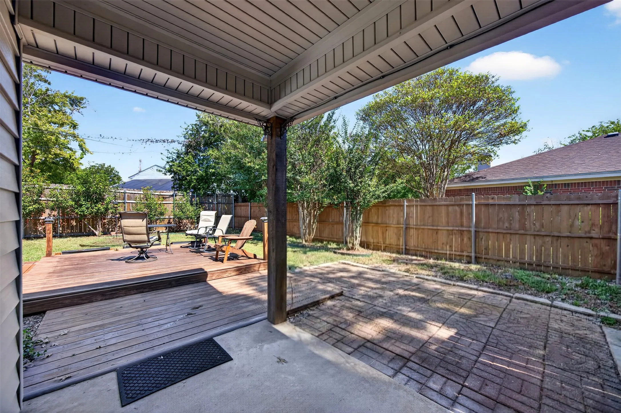 Covered patio with concrete flooring, wood deck, and wood privacy fencing
