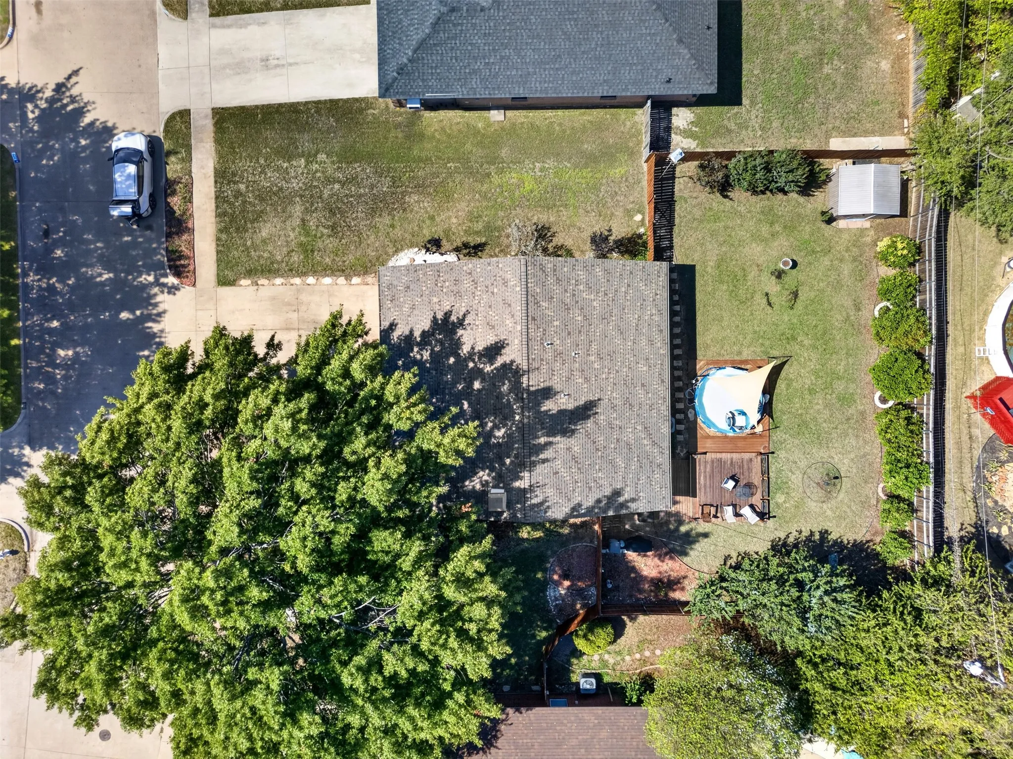 Expansive backyard featuring a manicured lawn, established trees, and a wooden deck