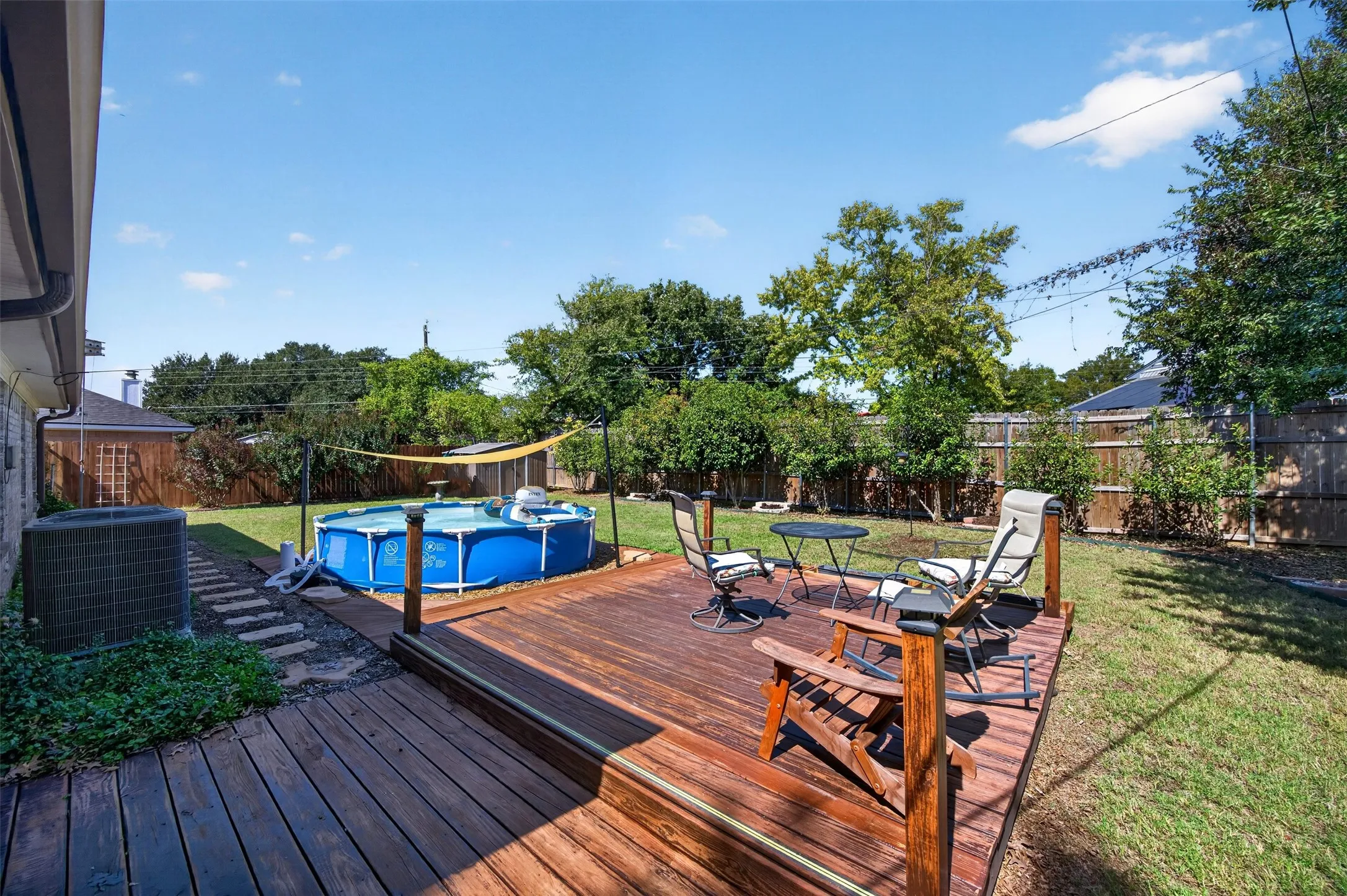 Expansive backyard featuring a wood deck, manicured lawn, and privacy fencing