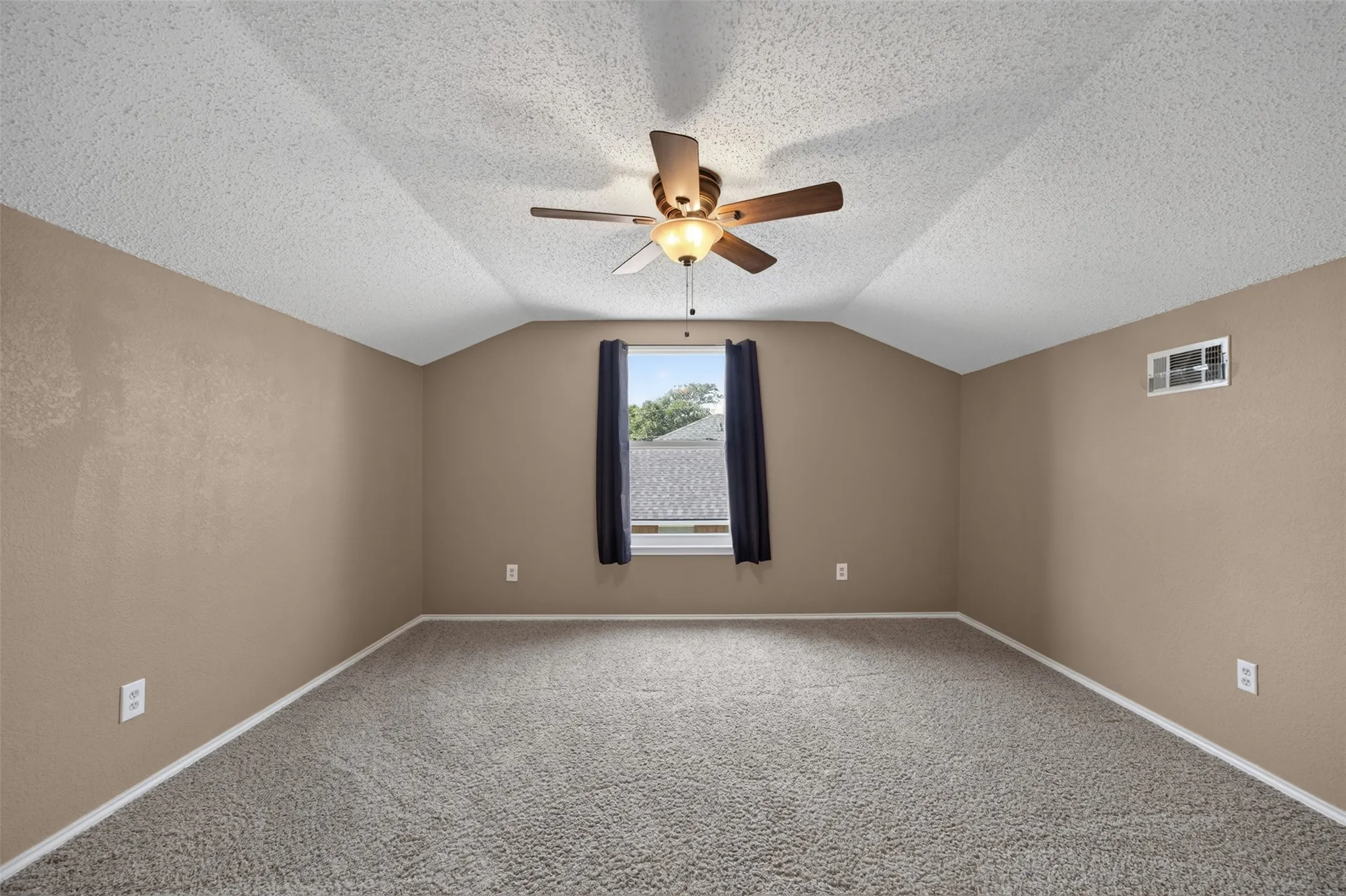 Vaulted ceiling, ceiling fan, neutral wall tones, carpet flooring, window with exterior landscape