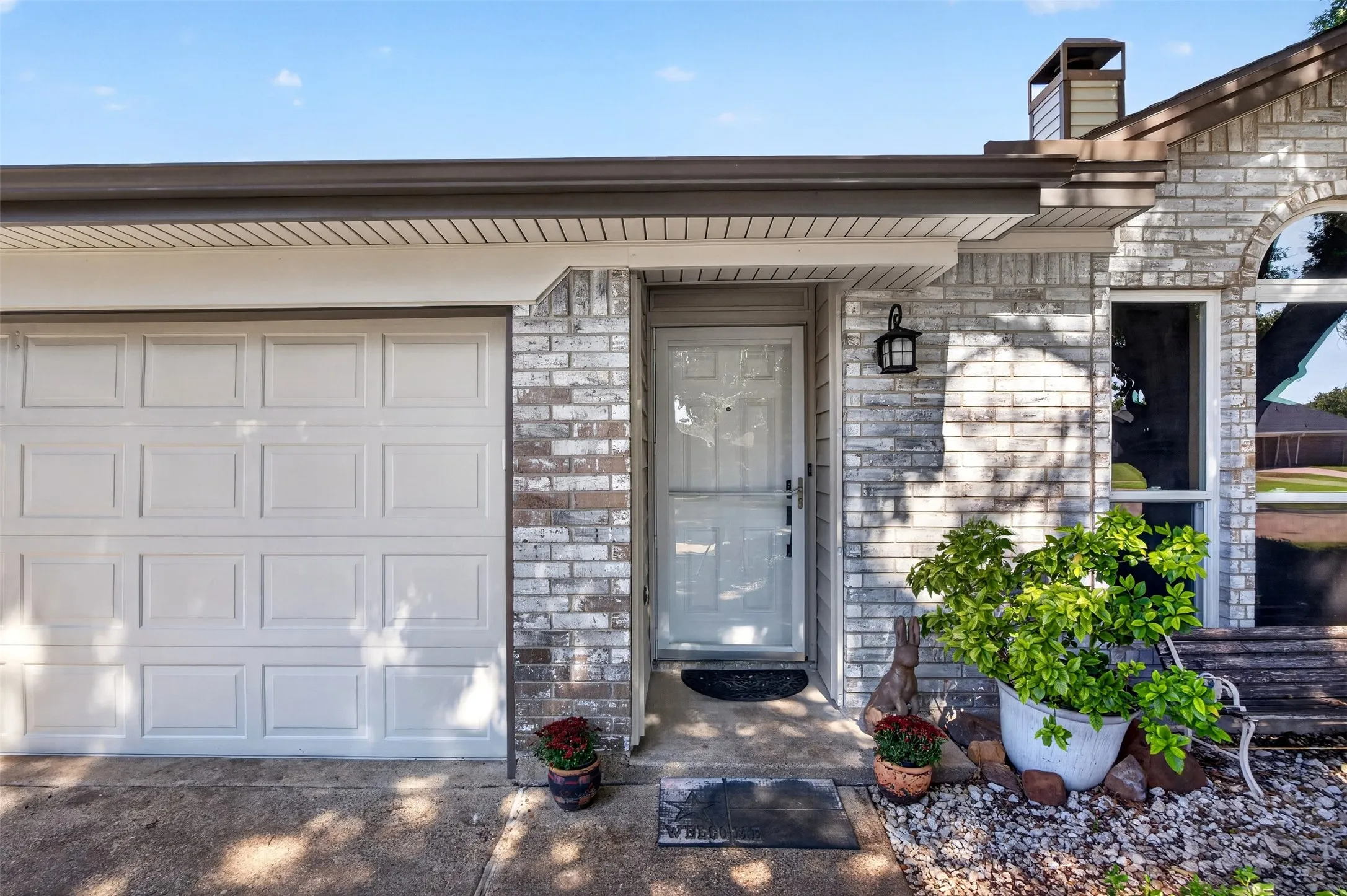 Brick exterior with a paneled garage door and a covered entryway