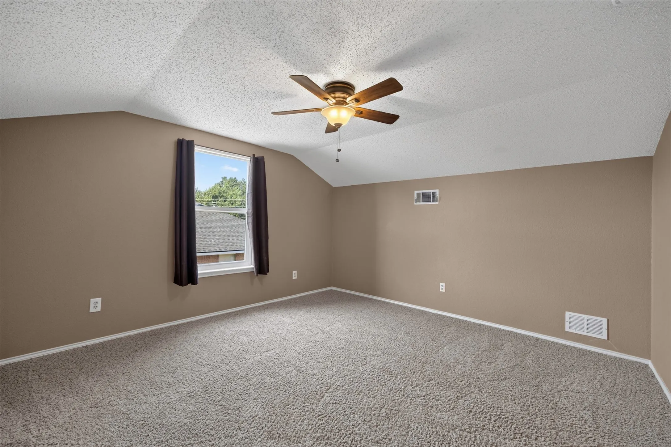Vaulted ceiling, ceiling fan with integrated lighting, carpeted flooring, and window with dark drapes