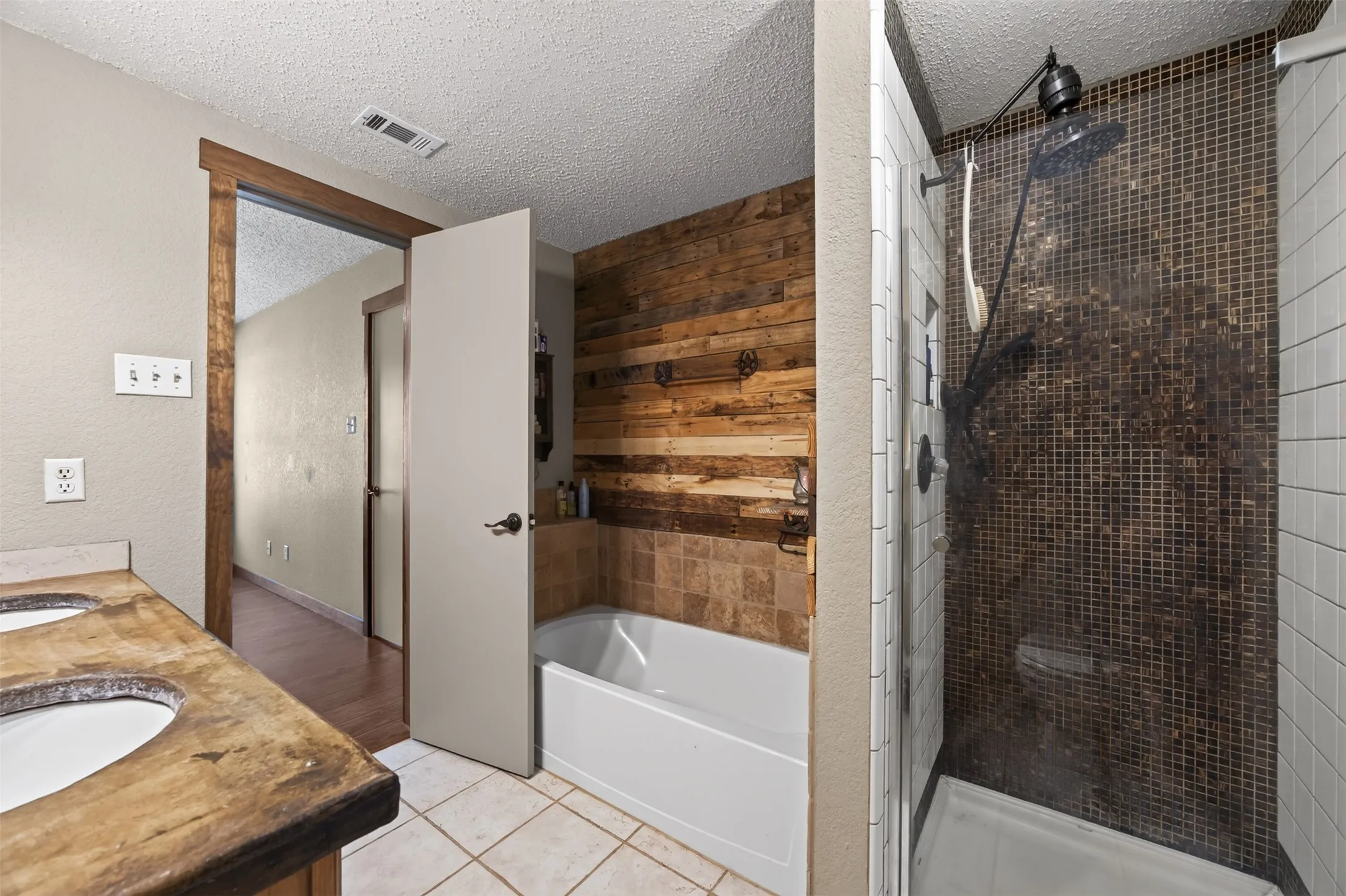 Dual vanity with integrated sinks, a tub/shower combination, and a separate walk-in shower with mosaic tile
