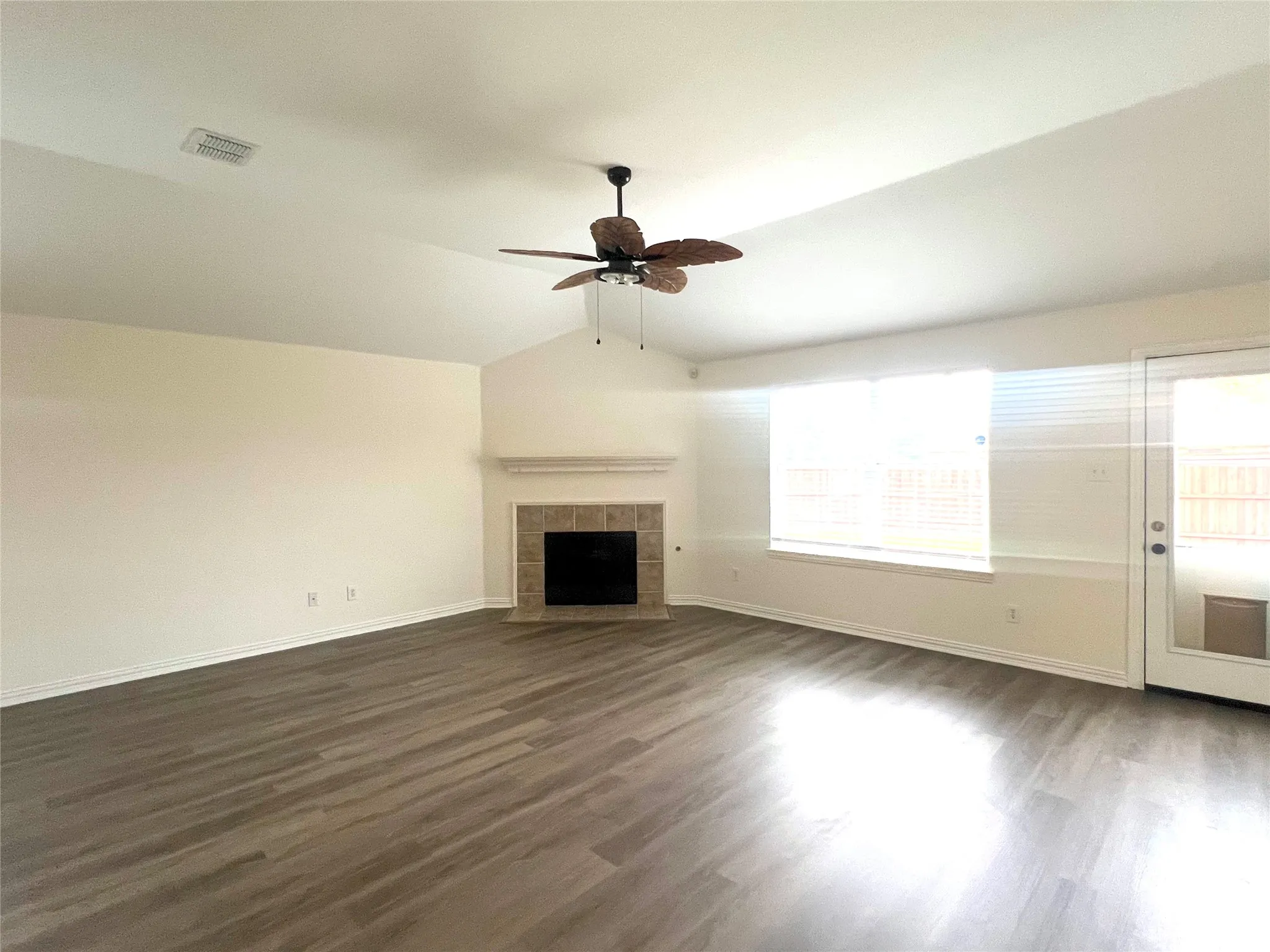 Unfurnished living room with vaulted ceiling, dark wood-type flooring, a fireplace, and ceiling fan