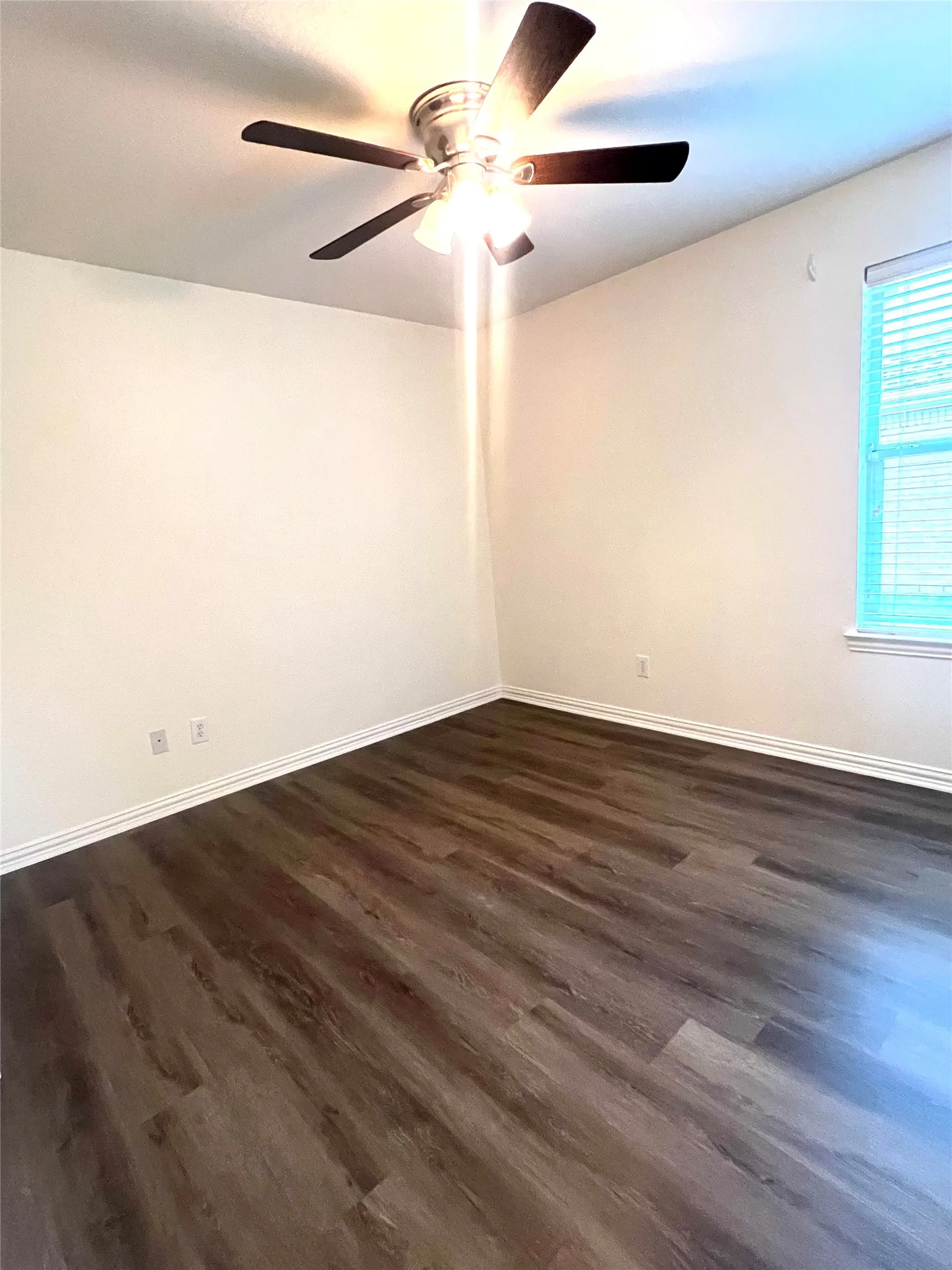 Empty room featuring dark wood-type flooring and baseboards