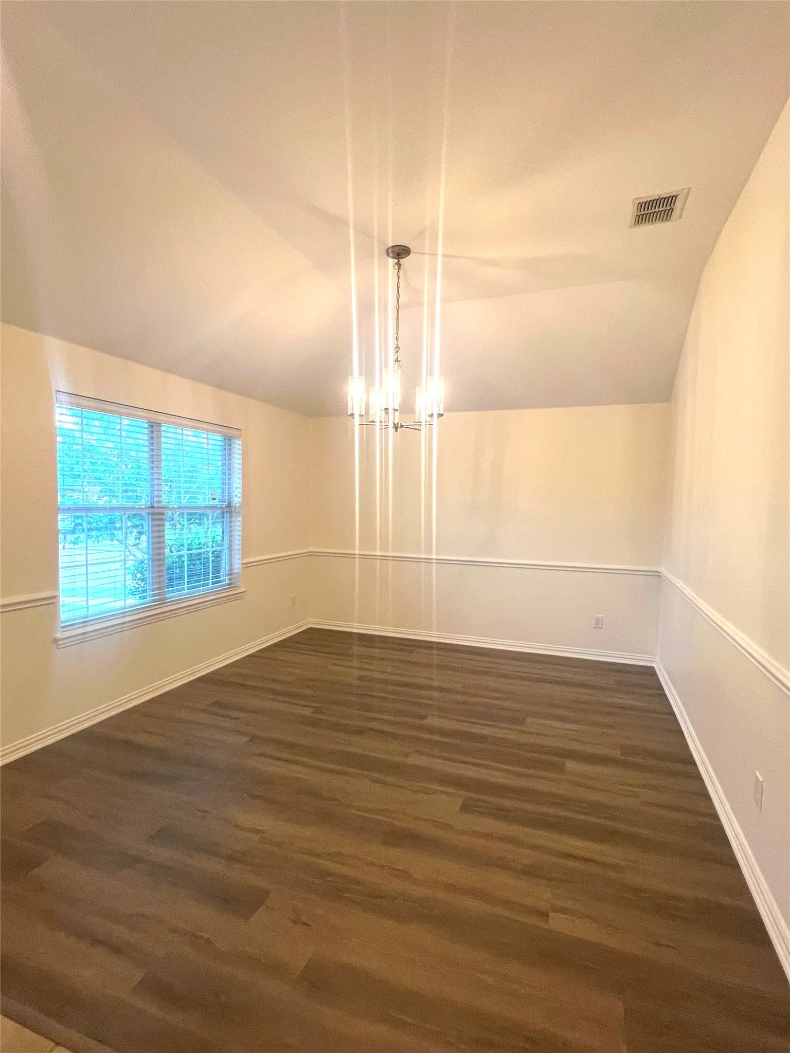 Unfurnished dining area featuring lofted ceiling, dark wood-style flooring, and a chandelier
