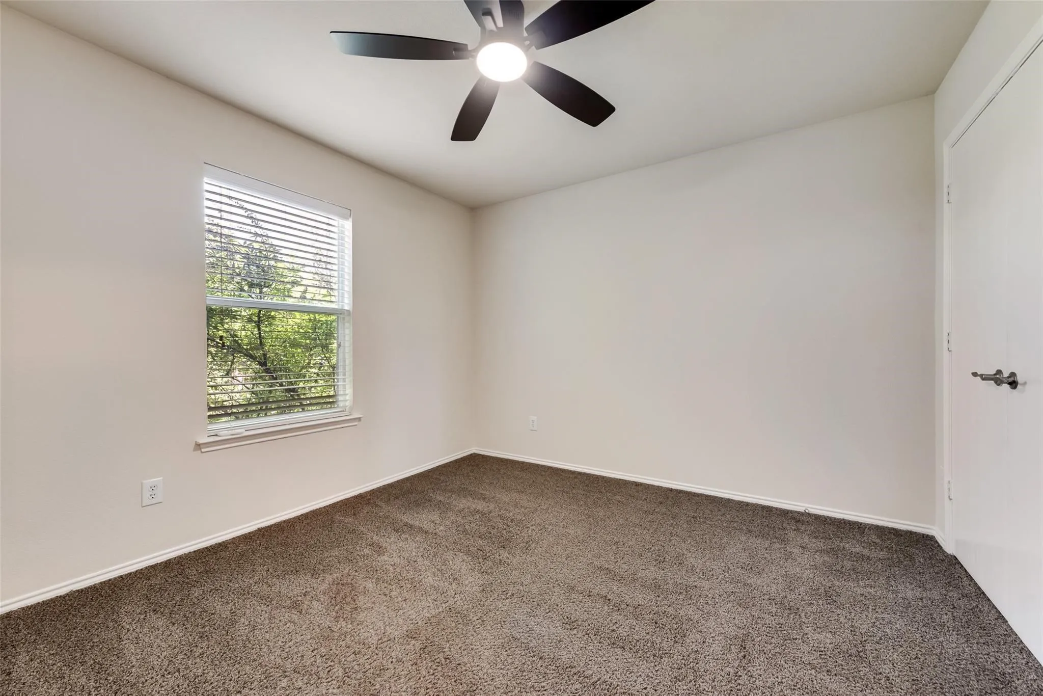 Neutral tone walls, brown carpeting, and a window with horizontal blinds