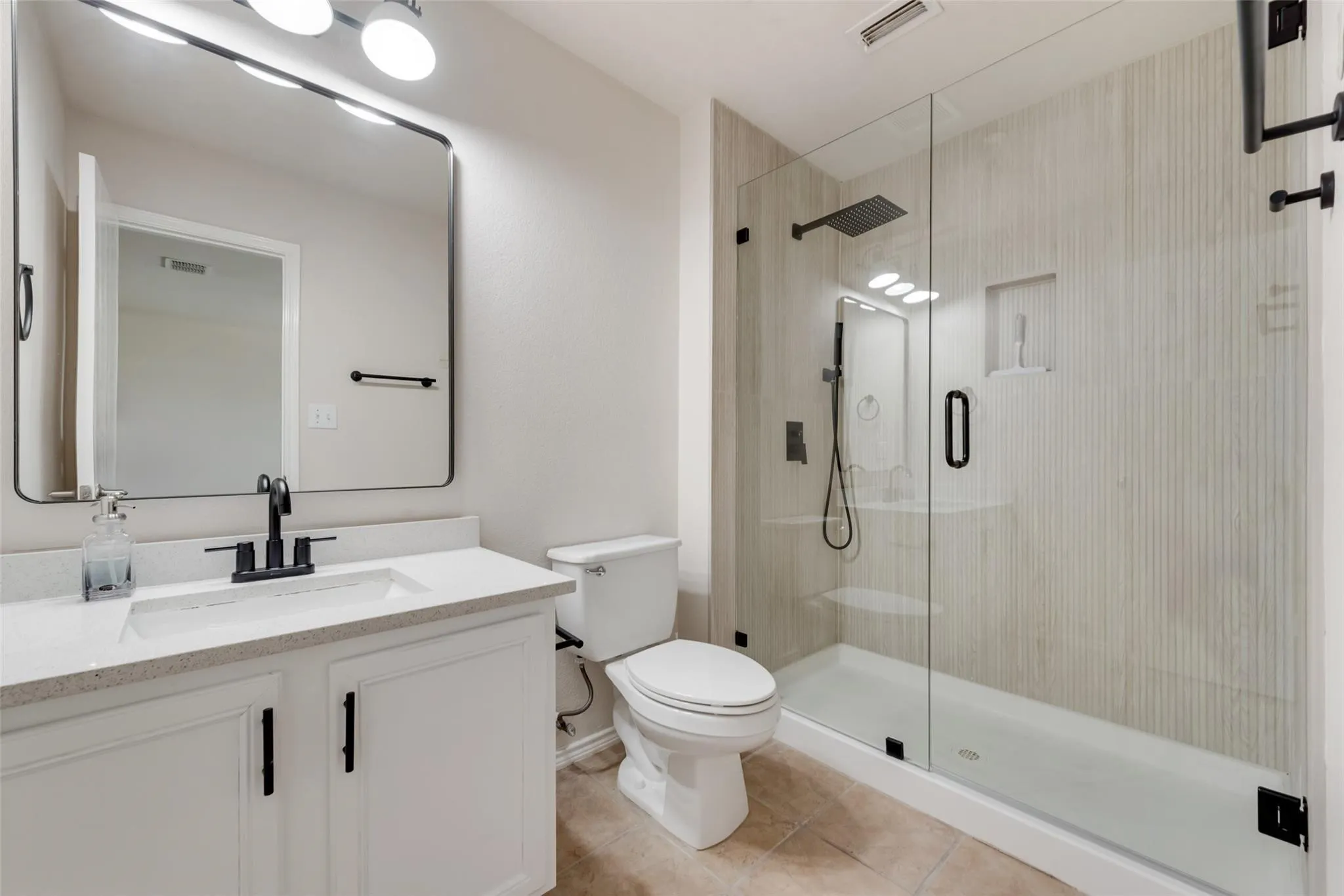 White vanity with integrated sink, black fixtures, and a large framed mirror