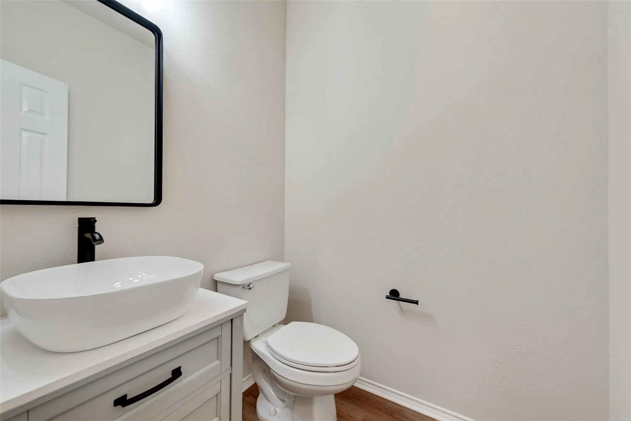 Contemporary vanity with a vessel sink, dark-finish faucet, and coordinating mirror
