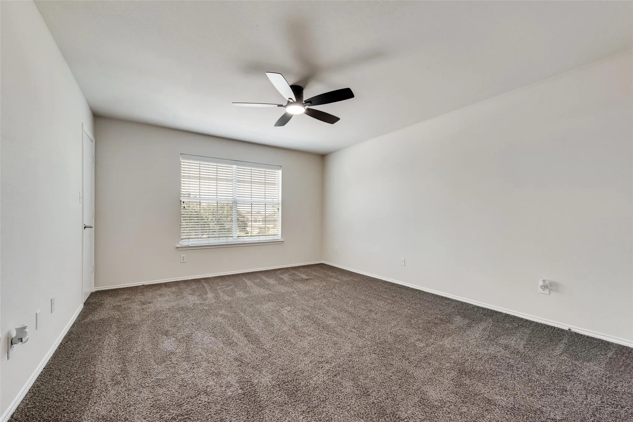 White walls, carpet flooring, window with blinds, and a ceiling fan with integrated lighting