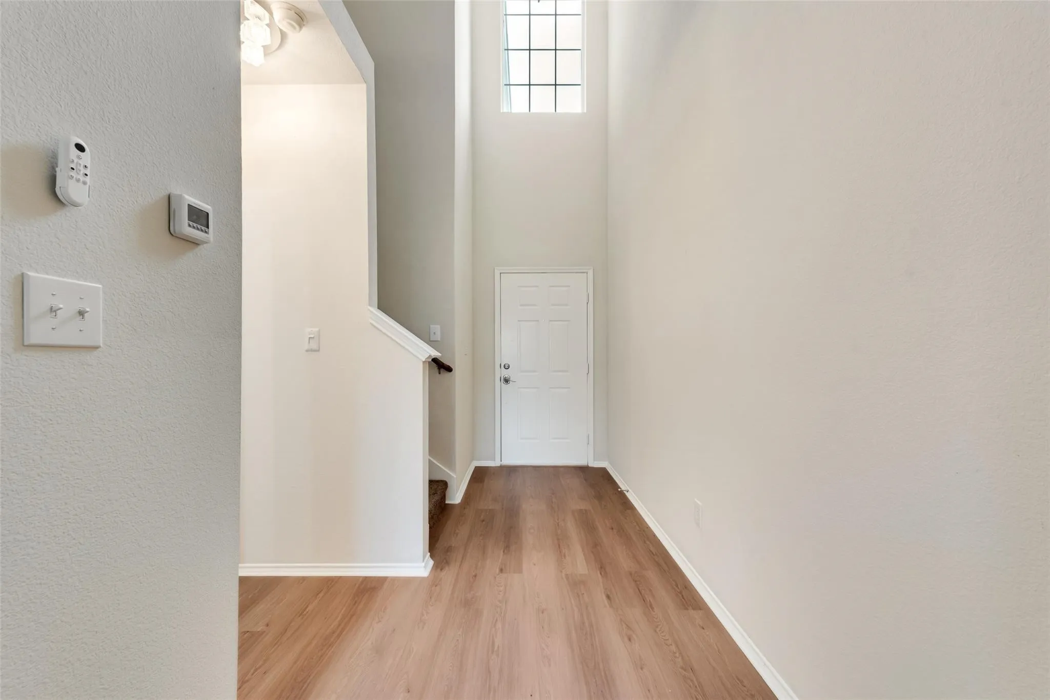 Entryway featuring wood-finish flooring, a white paneled door, and a high transom window