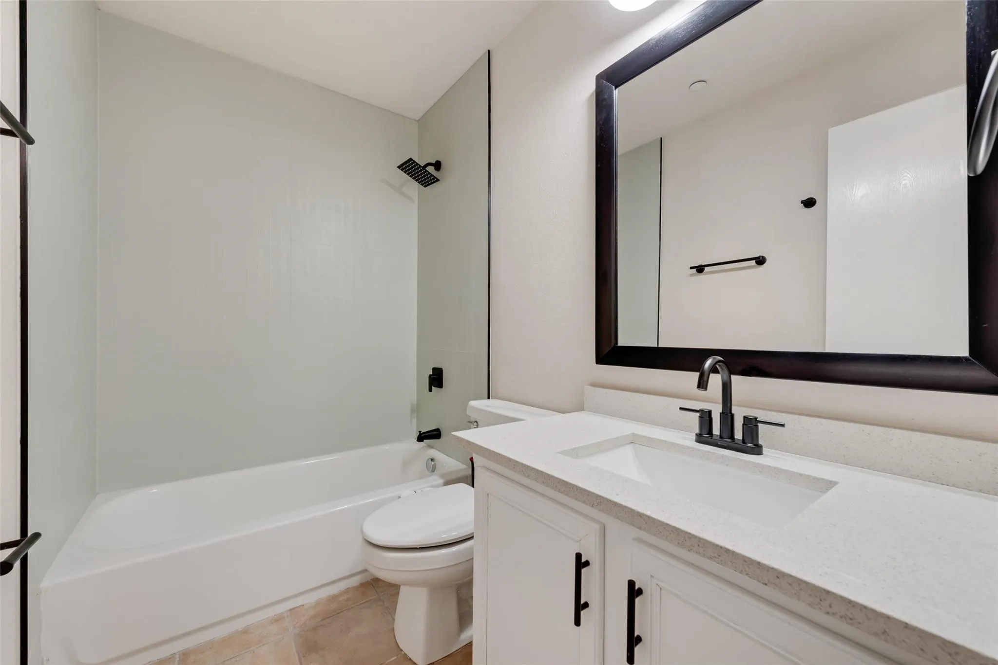 Bathroom featuring a white vanity with a light-toned countertop, rectangular undermount sink, and black fixtures