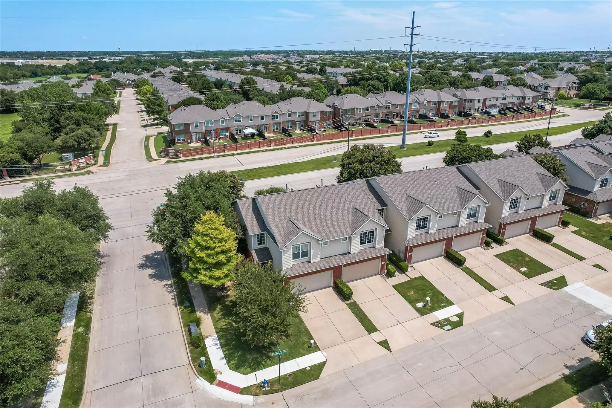 Aerial perspective showcasing a residential street, tree-lined sidewalks, and multiple properties with attached garages