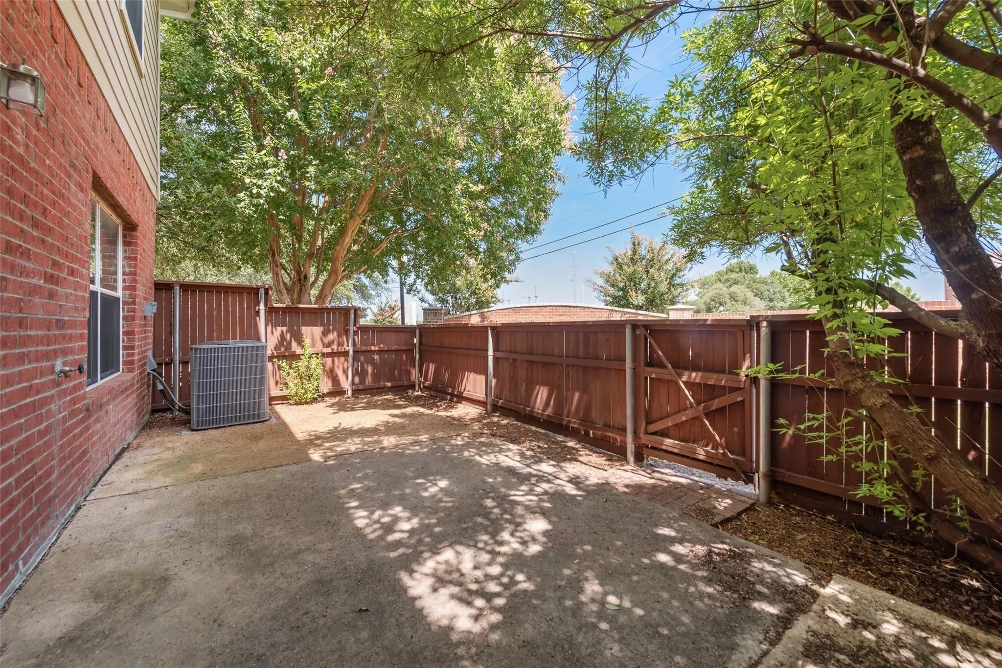 Concrete patio area featuring a full privacy fence with a gate