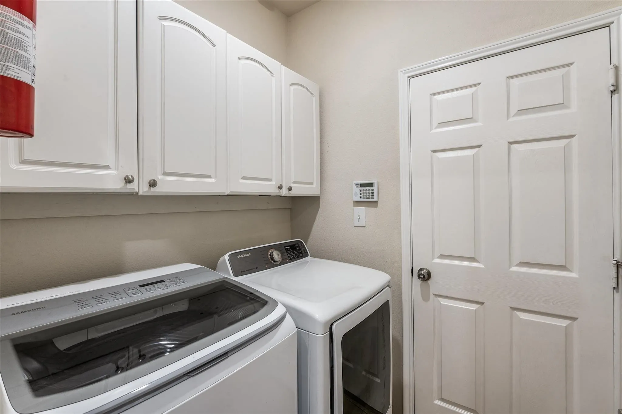 White shaker-style cabinetry with curved top panels, white paneled door, and neutral wall paint