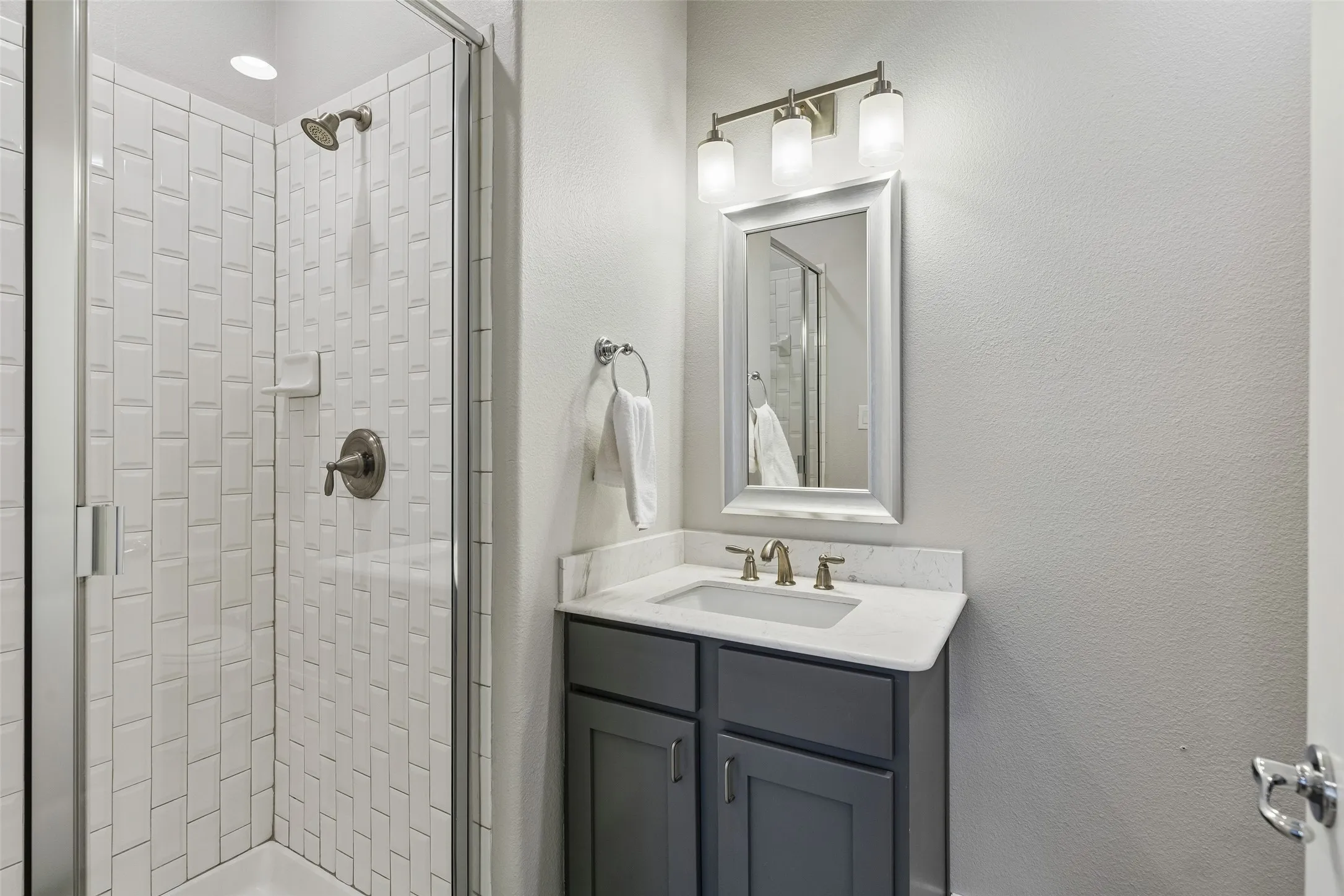 Shower with subway tile surround, clear glass enclosure, and recessed lighting